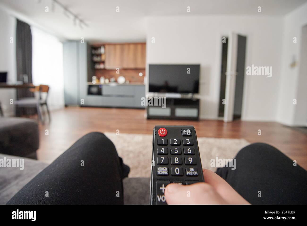 Primo piano del telecomando in mano sullo sfondo sfocato dell'appartamento Foto Stock