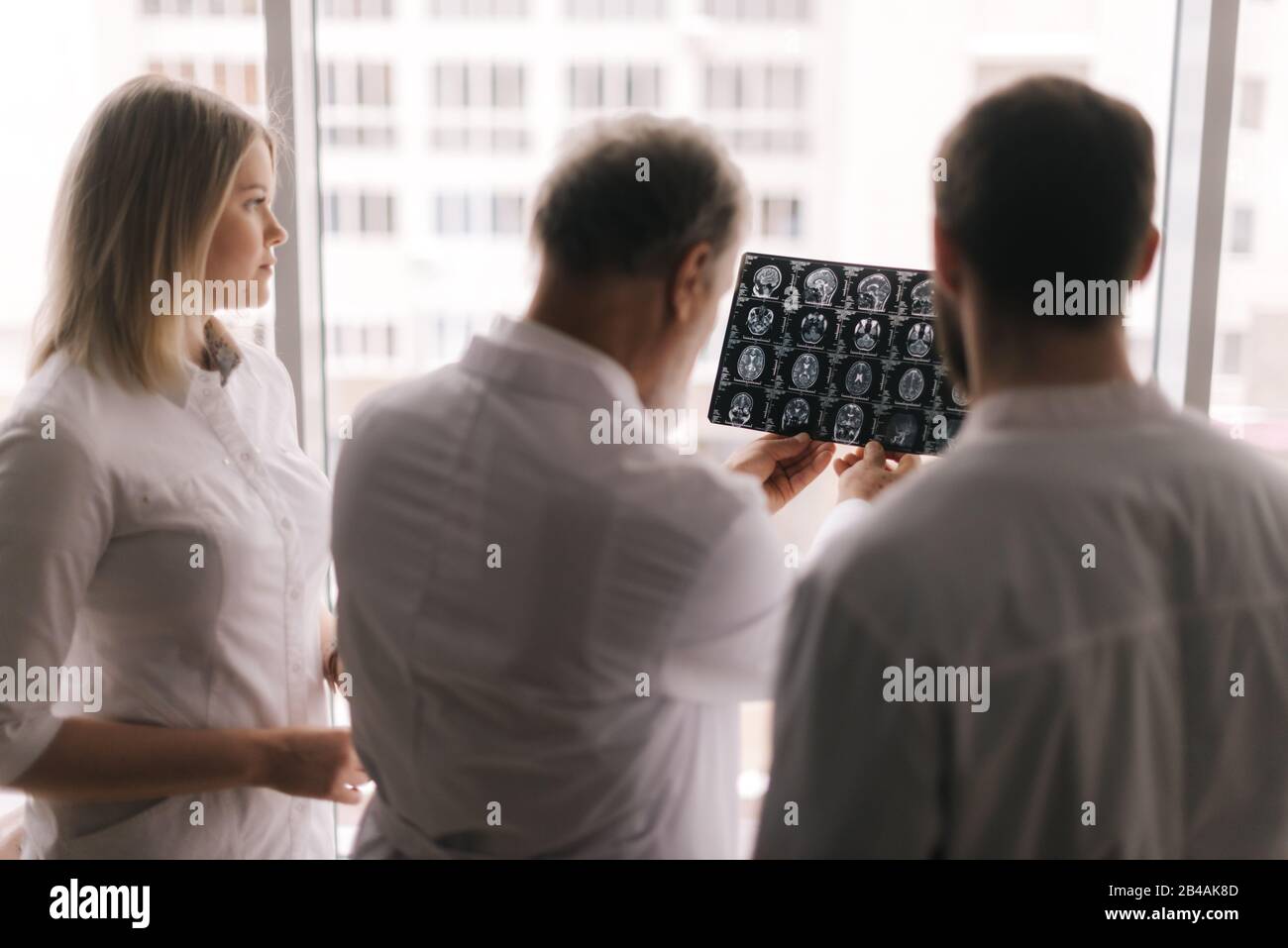 Il team di esperti medici discute i risultati di una scansione RM della testa del paziente Foto Stock