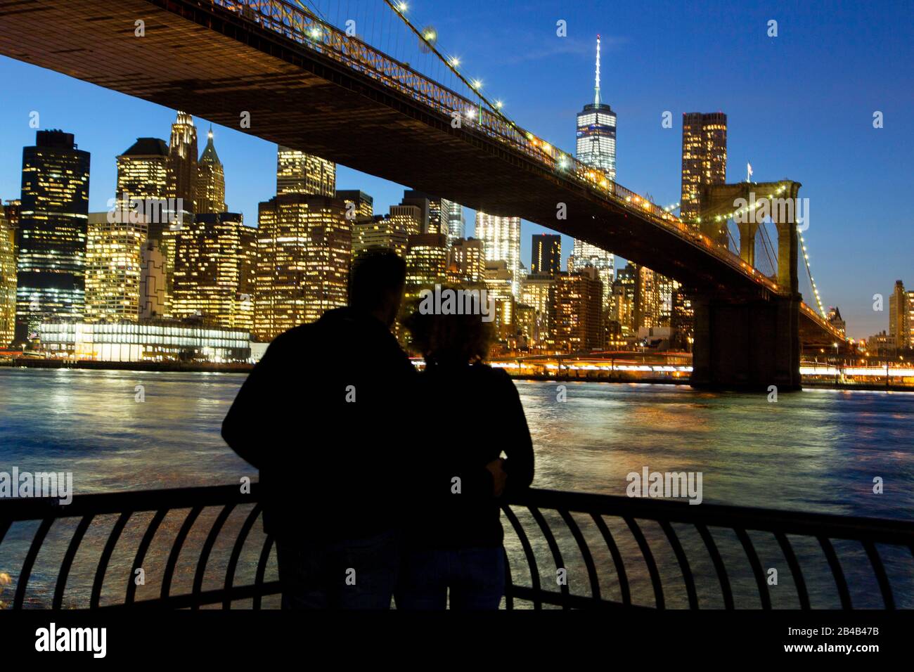 Stati Uniti, New York, Manhattan, Brroklyn Bridge di fronte allo skyline notturno con Il One World Trade Center (1WTC), coppia Foto Stock