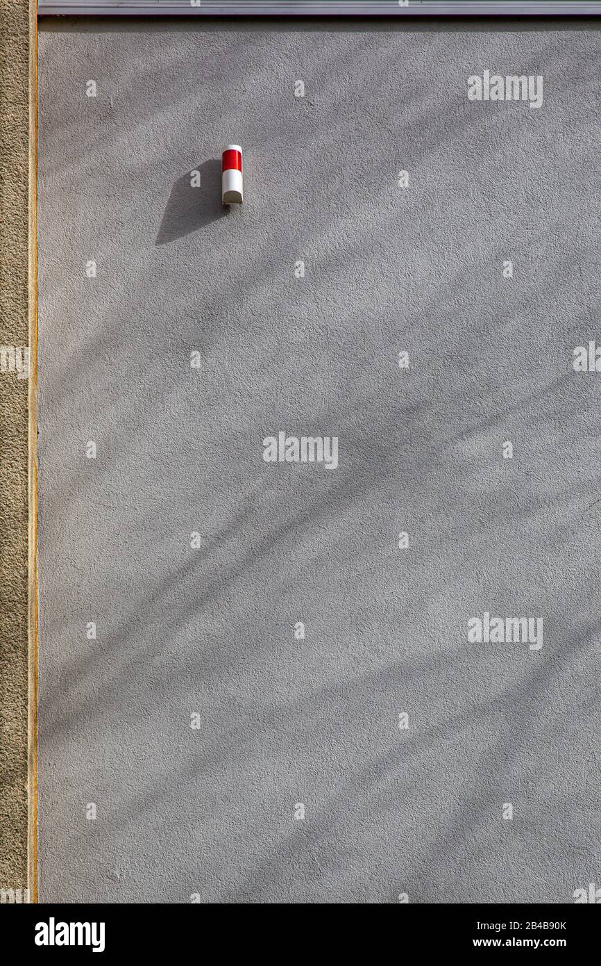 una luce rossa di allarme su una facciata di cemento grigio con ombre di un albero - copia spazio Foto Stock