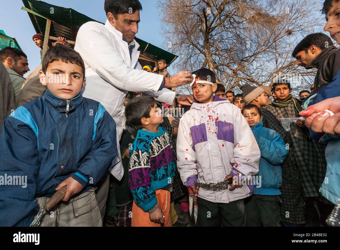 India, stato di Jammu e Kashmir, Srinagar, processione annuale Ashura, inizio del mese musulmano Muharram, celebrazione in onore del martirio del profeta sciita Husayn, bambino che riceve assistenza dopo una sessione di mortificazione, con catene dotate di lame affilate alle loro estremità (Mataam) Foto Stock