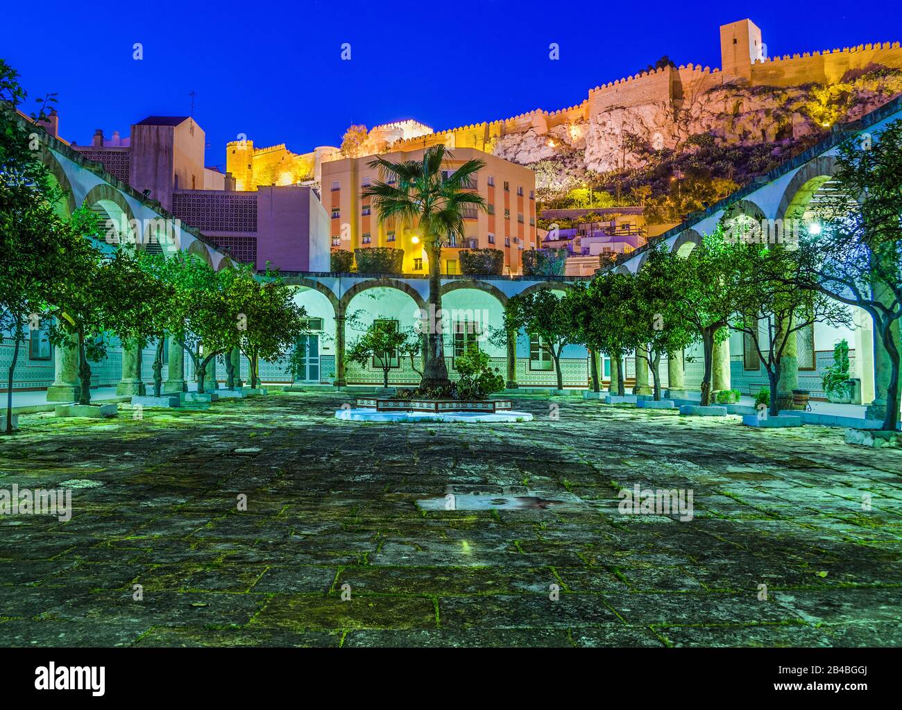 Patio de Los Naranjos nell'ora blu, con l'Alcazaba, illuminato sullo sfondo, città di Almeria, Andalusia, Spagna Foto Stock