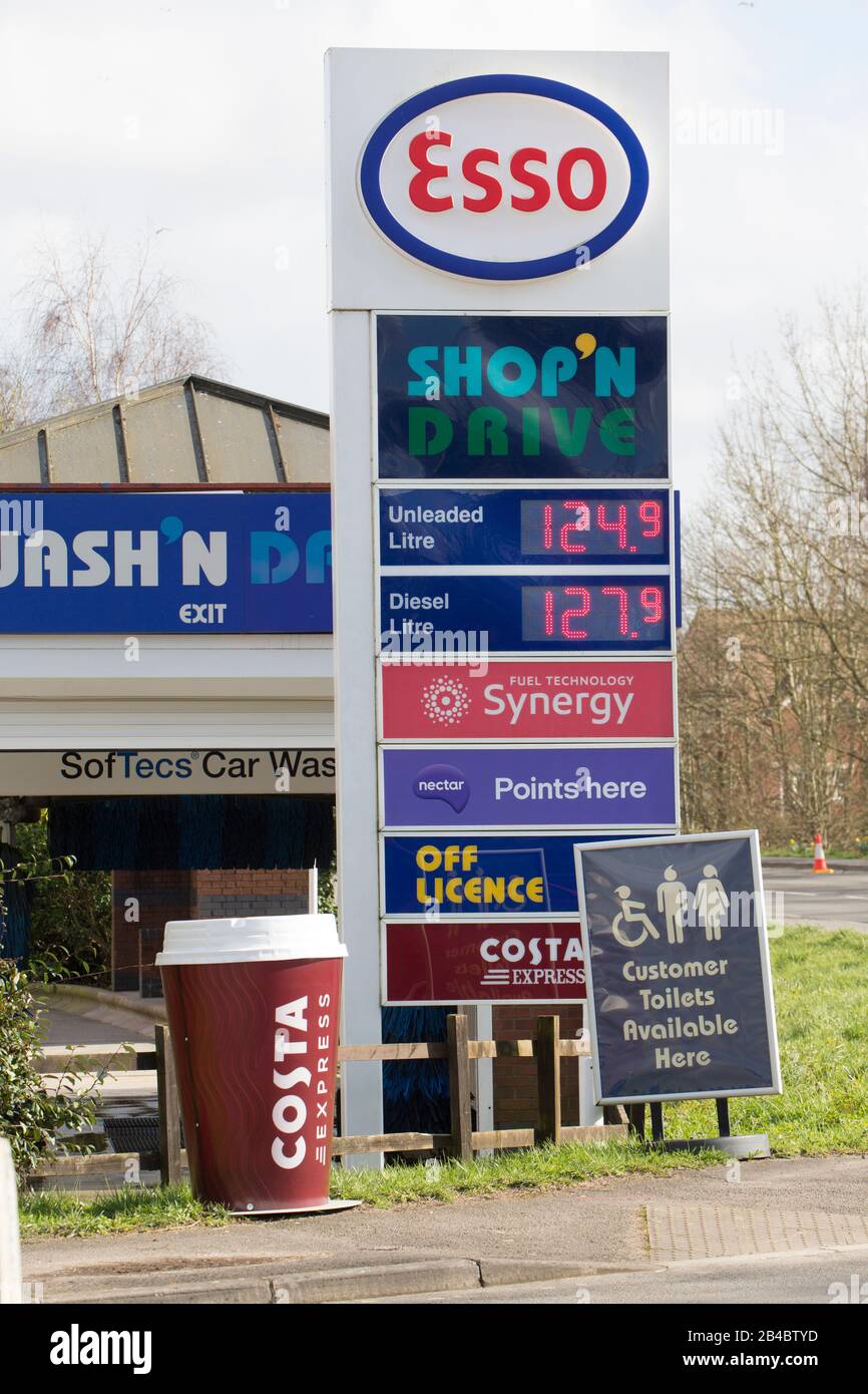 Una stazione di carburante esso che fa pubblicità ai prezzi del carburante, servizi igienici del cliente e un cartello Costa Coffe. Dorset Inghilterra GB Foto Stock