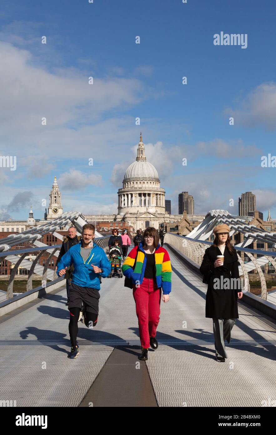 Persone che attraversano il Millennium Bridge di fronte alla Cattedrale di St Pauls in una giornata di sole a marzo, nel centro di Londra, Londra Inghilterra Regno Unito Foto Stock