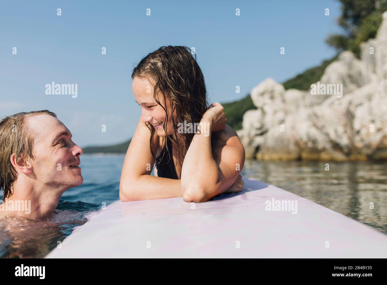 Junge Frau und junger Mann auf einem Surfbrett bzw im Wasser, Cres, Kroatien Foto Stock