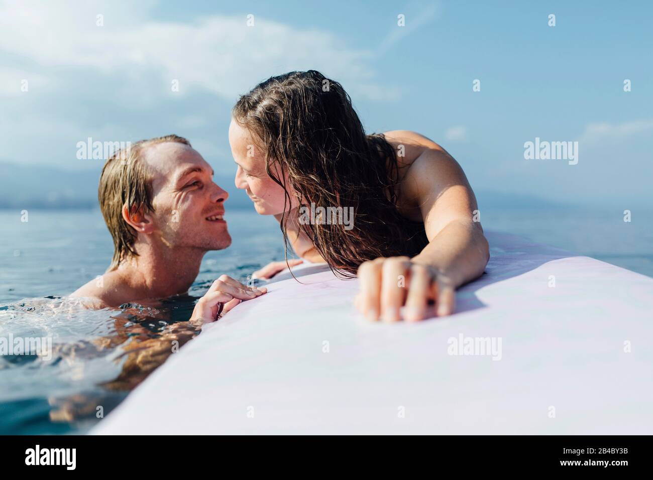 Junges Paar beim Baden & auf dem Surfbrett a Cres, Kroatien Foto Stock