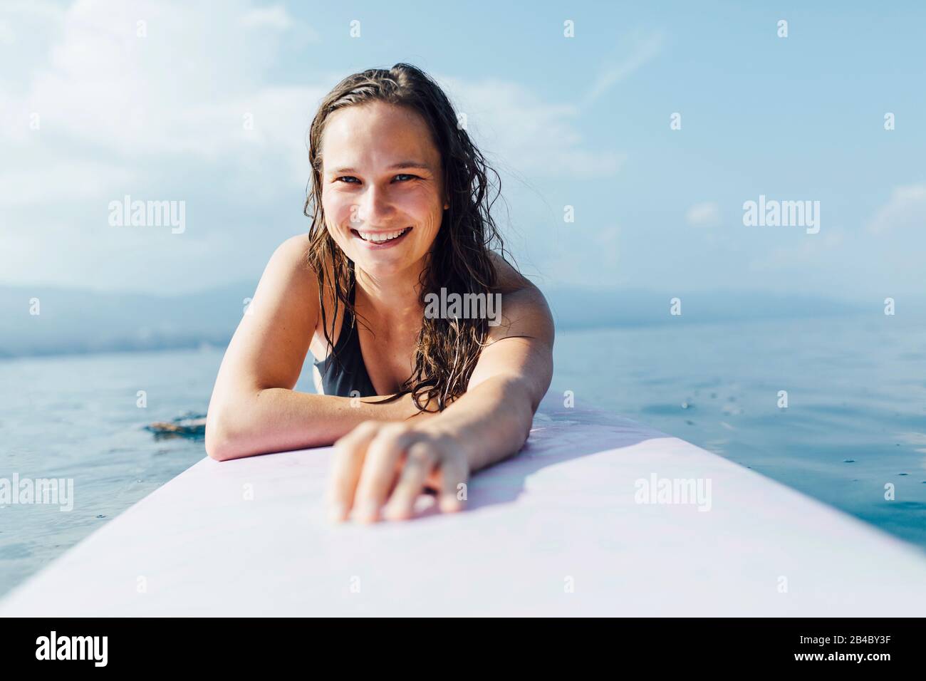 Junge Frau 20-30 Jahre liegt auf Surfbrett und genießt die Sonne, Kroatien Foto Stock