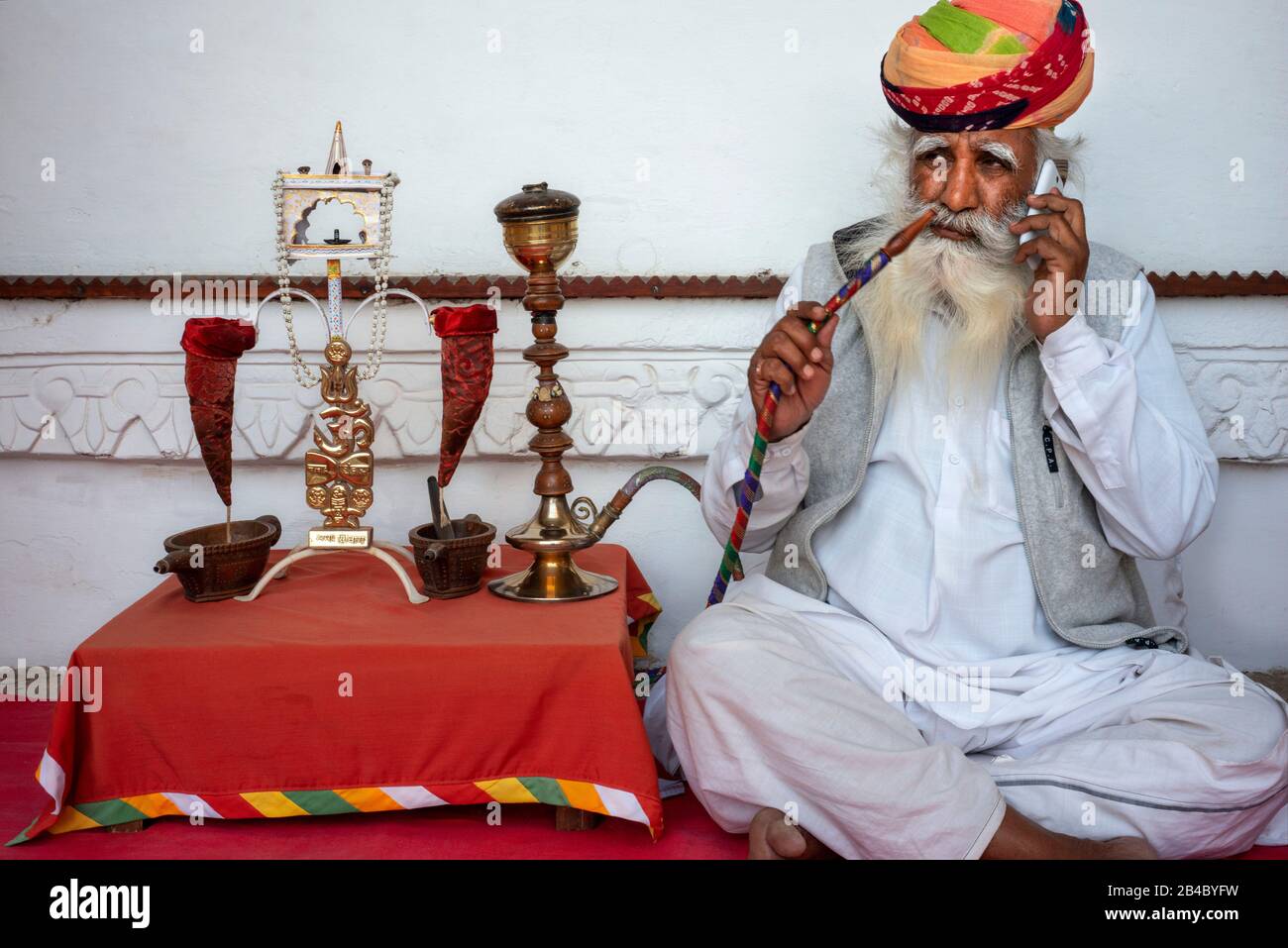 L'uomo indiano invecchiato con la barba bianca lunga e l'oppio fumante turbante colorful da un tubo dell'acqua all'interno del forte di Mehrangarh, Jodhpur, Rajasthan, India. Questo è o Foto Stock