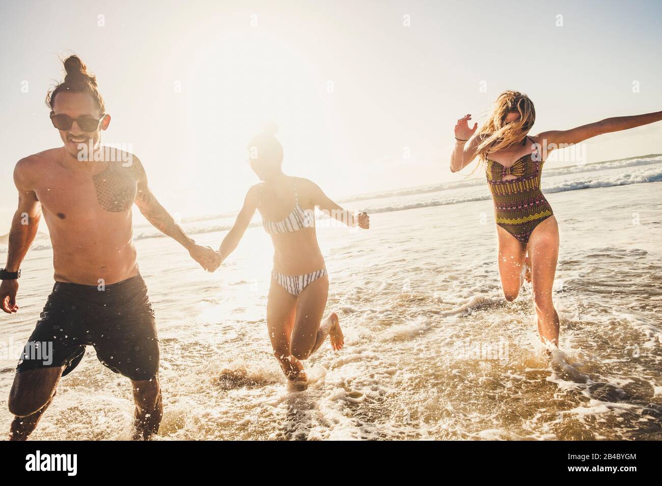 Gruppo di giovani amici godersi con divertimento la vacanza estiva che corre in spiaggia all'acqua in giocosa attività all'aperto di svago insieme - uomini giovani e donne Foto Stock
