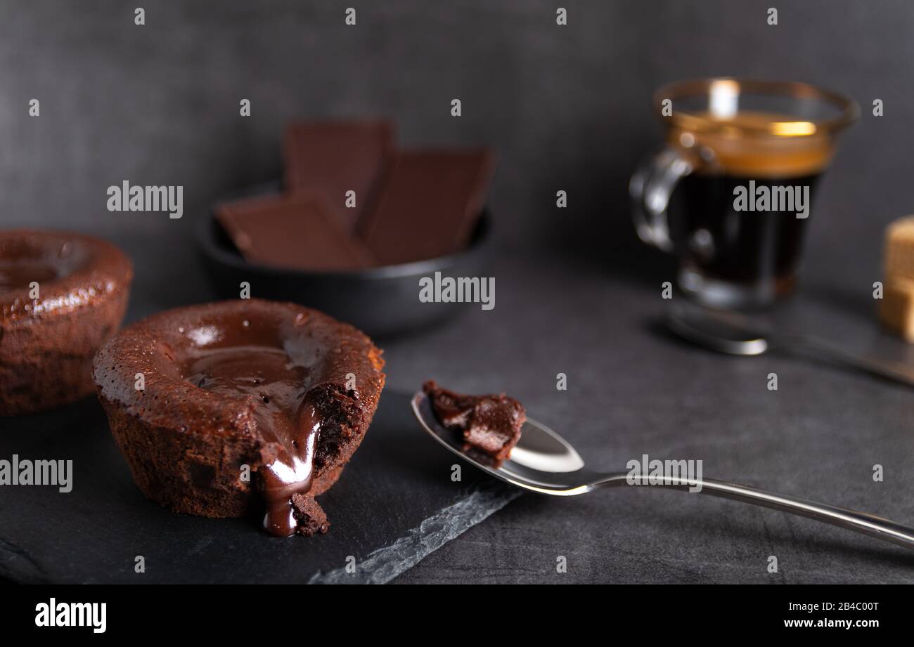 Torta di lava al cioccolato fatta in casa su un piatto nero con un caffè su sfondo nero Foto Stock