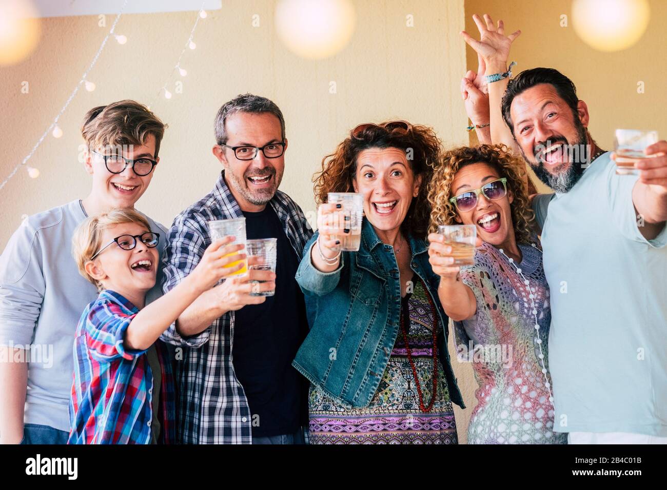 Gruppo di persone caucasiche uomini e donne di età diversa da bambini a adolescenti a adulti godere e celenrate insieme tostare con occhiali e avere un sacco di divertimento per l'amicizia Foto Stock