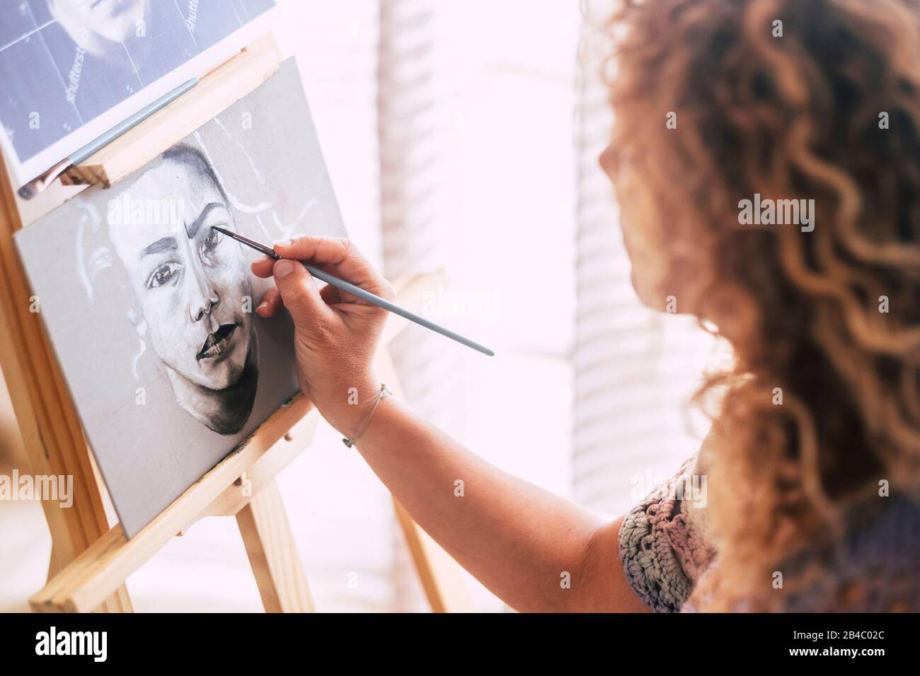 Arte, creatività e concetto di persone - closeup caucasico di pittura a mano donna e disegno di un ritratto a casa in bianco e nero - attività artistica di svago - pennello su tela per creare Foto Stock