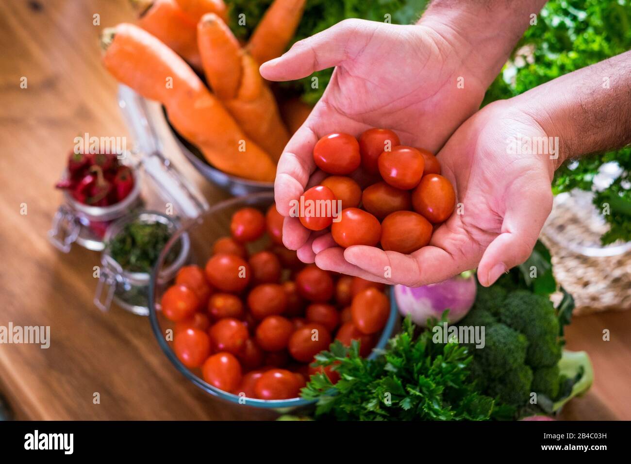 Verdure per vegetariano o vegano o sano stile di vita alimentare persone - misto di colori e vitamine sul tavolo pronto per essere mangiato per perdita di peso e salute - uomo caucasico prendendo pomodori ciliegini Foto Stock
