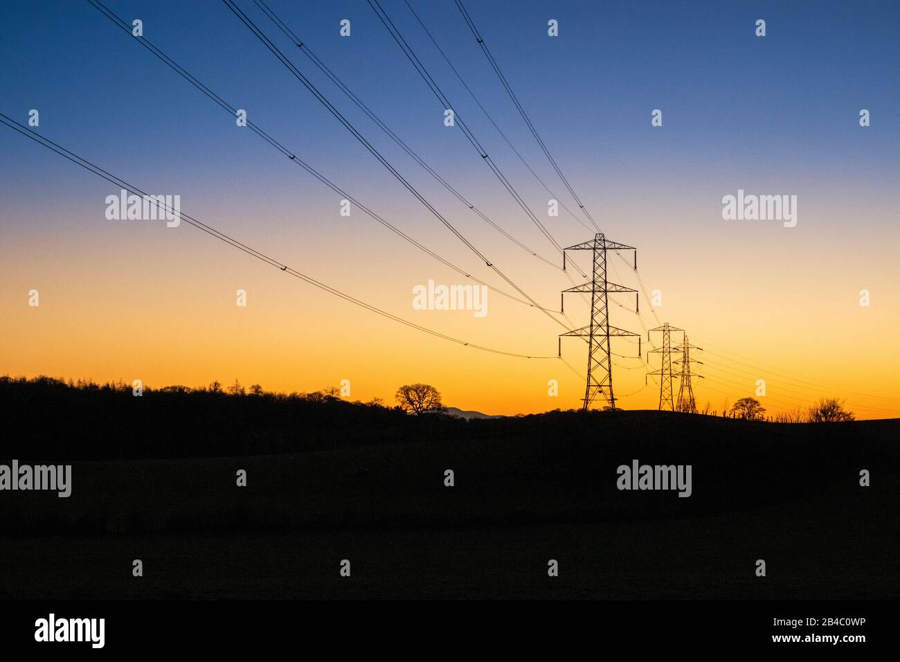 Un tramonto invernale dietro le linee elettriche e i tralicci a Milton vicino Brampton, Cumbria Regno Unito Foto Stock