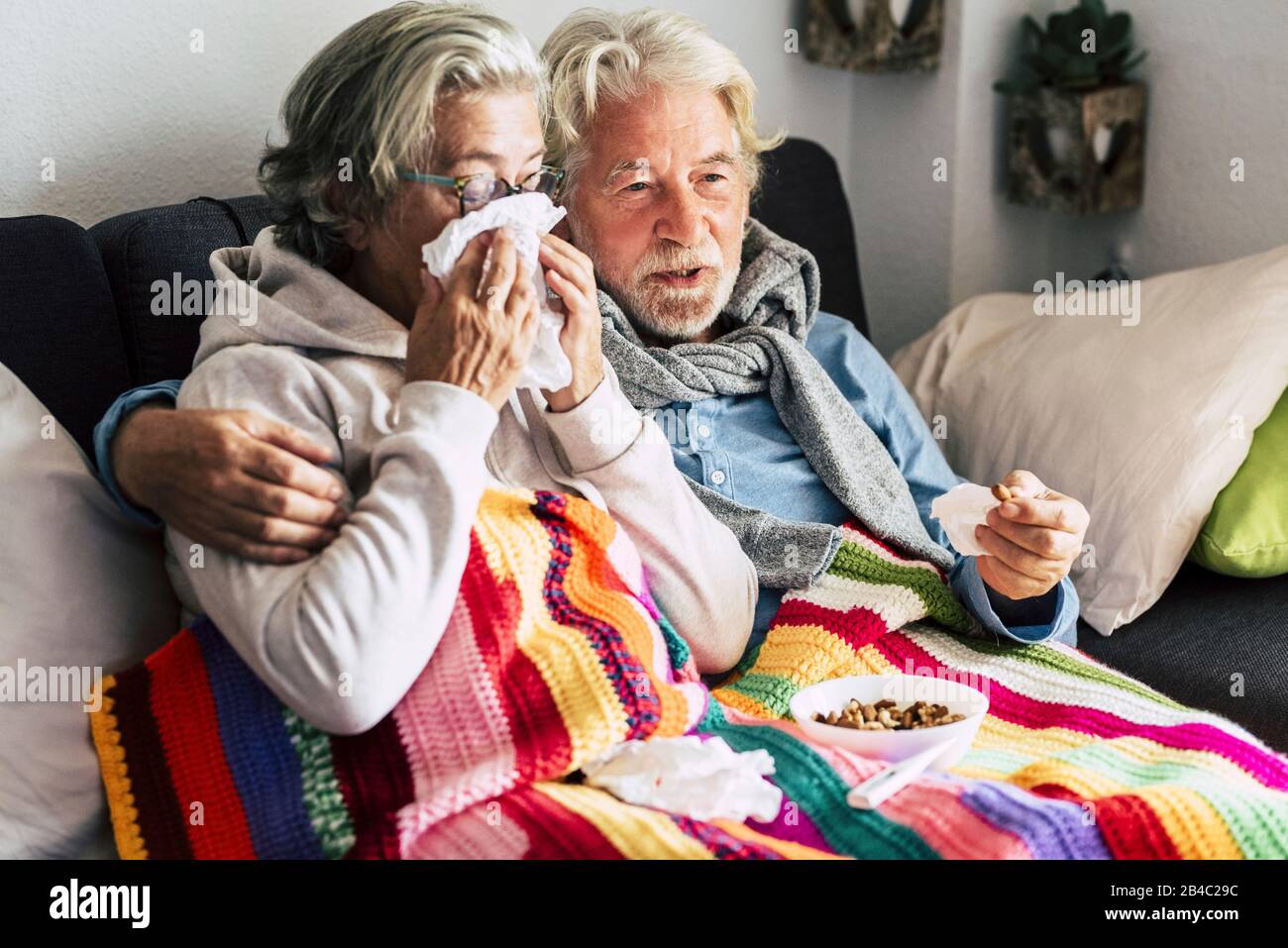 Coppia di anziani anziani a casa con malattia fredda invernale stagionale si siedono sul sof insieme per sempre - problemi di salute per uomo e donna pensionati con capelli bianchi Foto Stock