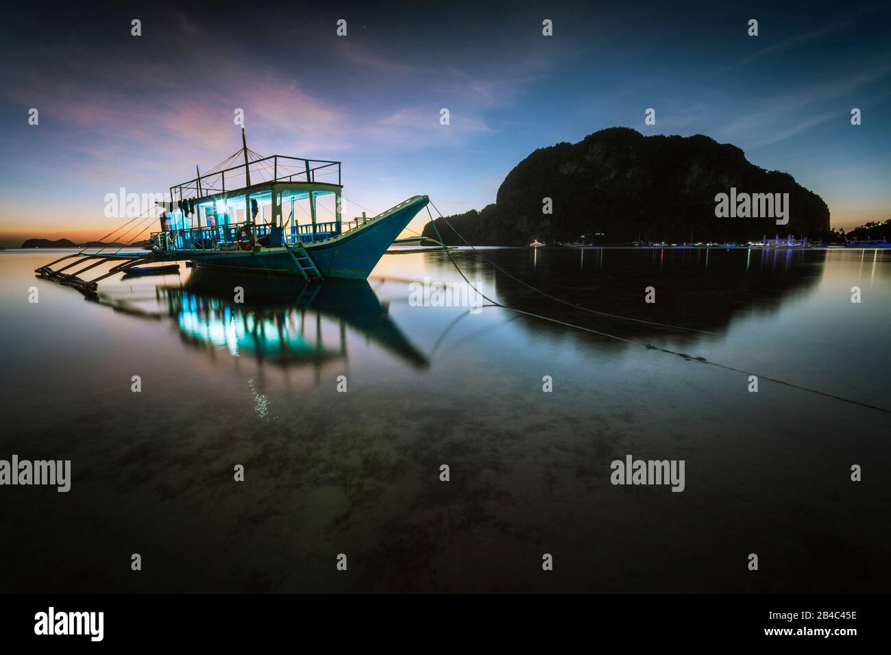 Porto tropicale baia di mare con barca banca in serata. Ora blu in laguna nelle Filippine, Palawan, El Nido. Tranquillo scenario da sogno, lunga esposizione. Foto Stock