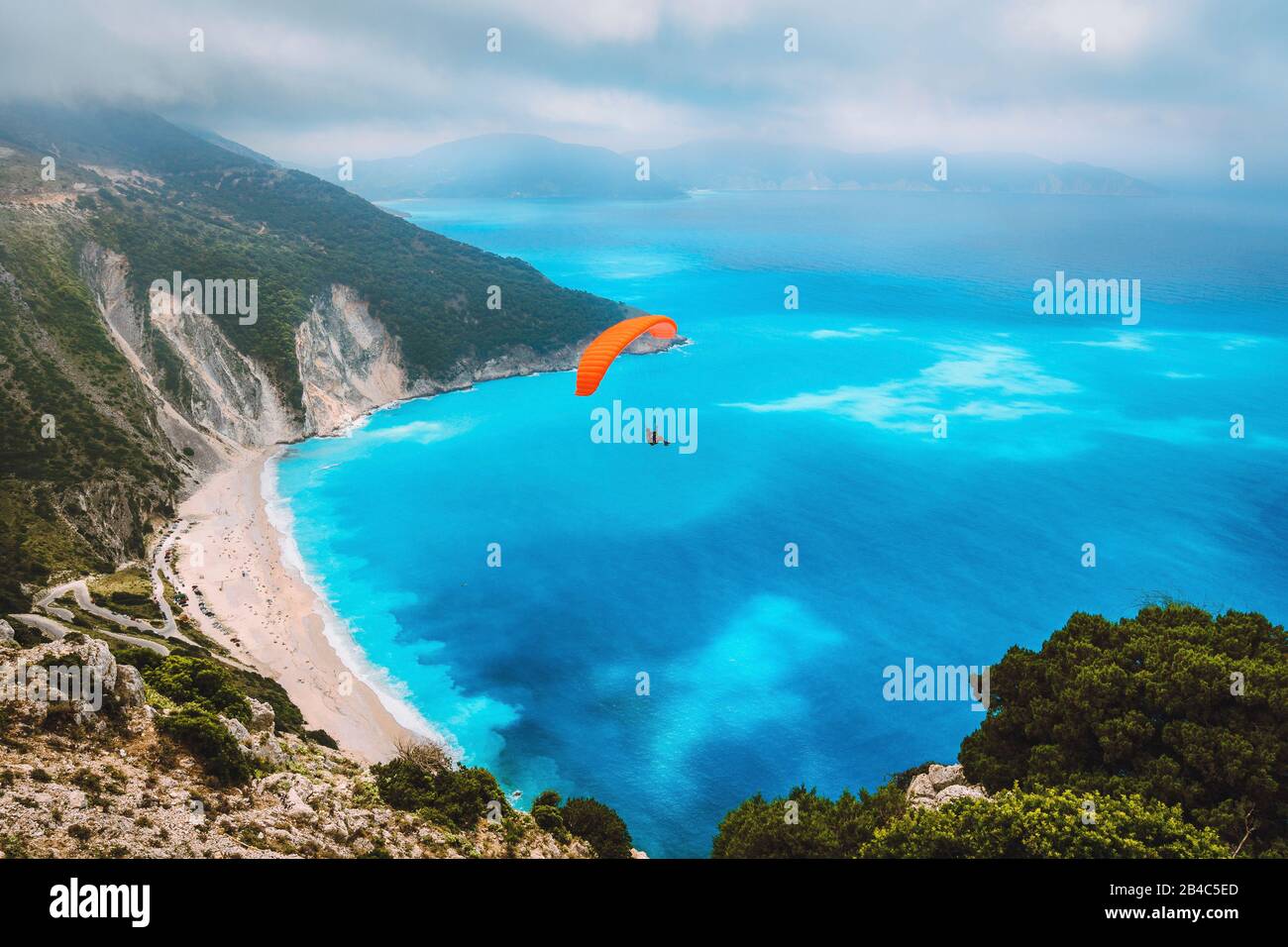 Veduta aerea del parapendio che vola sulla splendida spiaggia di Myrtos. Incredibili colori dell'acqua e splendida costa sull'isola di cefalonia, Grecia. Foto Stock
