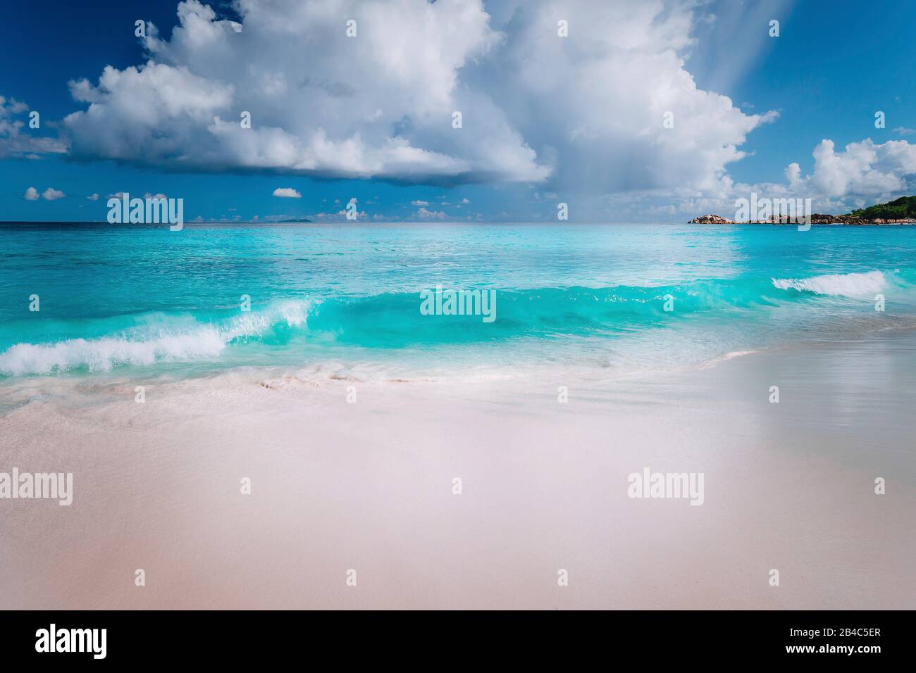 Bella onda bianco il rotolamento verso la spiaggia sabbiosa tropicale. Splendida soffici nuvole sopra il mare blu. Seychelles Grand Anse, La Digue, Seychelles. Foto Stock
