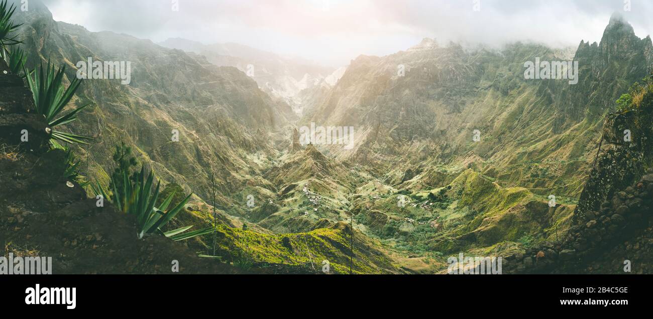 XO-Xo valle con cime dure circondata da montagne. Le piste sono coperte da piante di agave. Piccolo villaggio locale situato nella valle. Isola Di Santo Antao, Capo Verde. Scatto panoramico. Foto Stock
