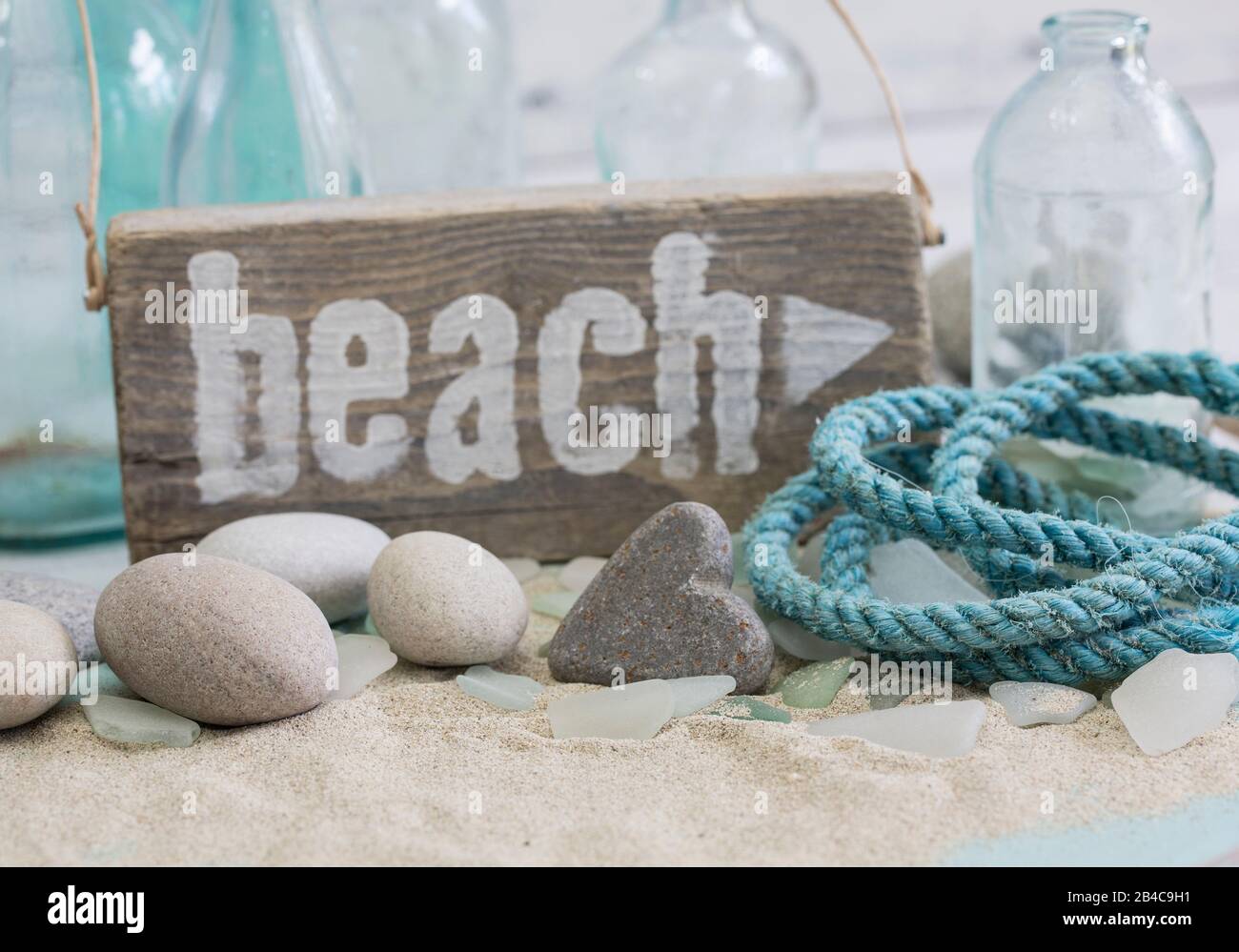 Ancora vita nautica con segno di spiaggia in legno, cuore di pietra e vecchia corda Foto Stock