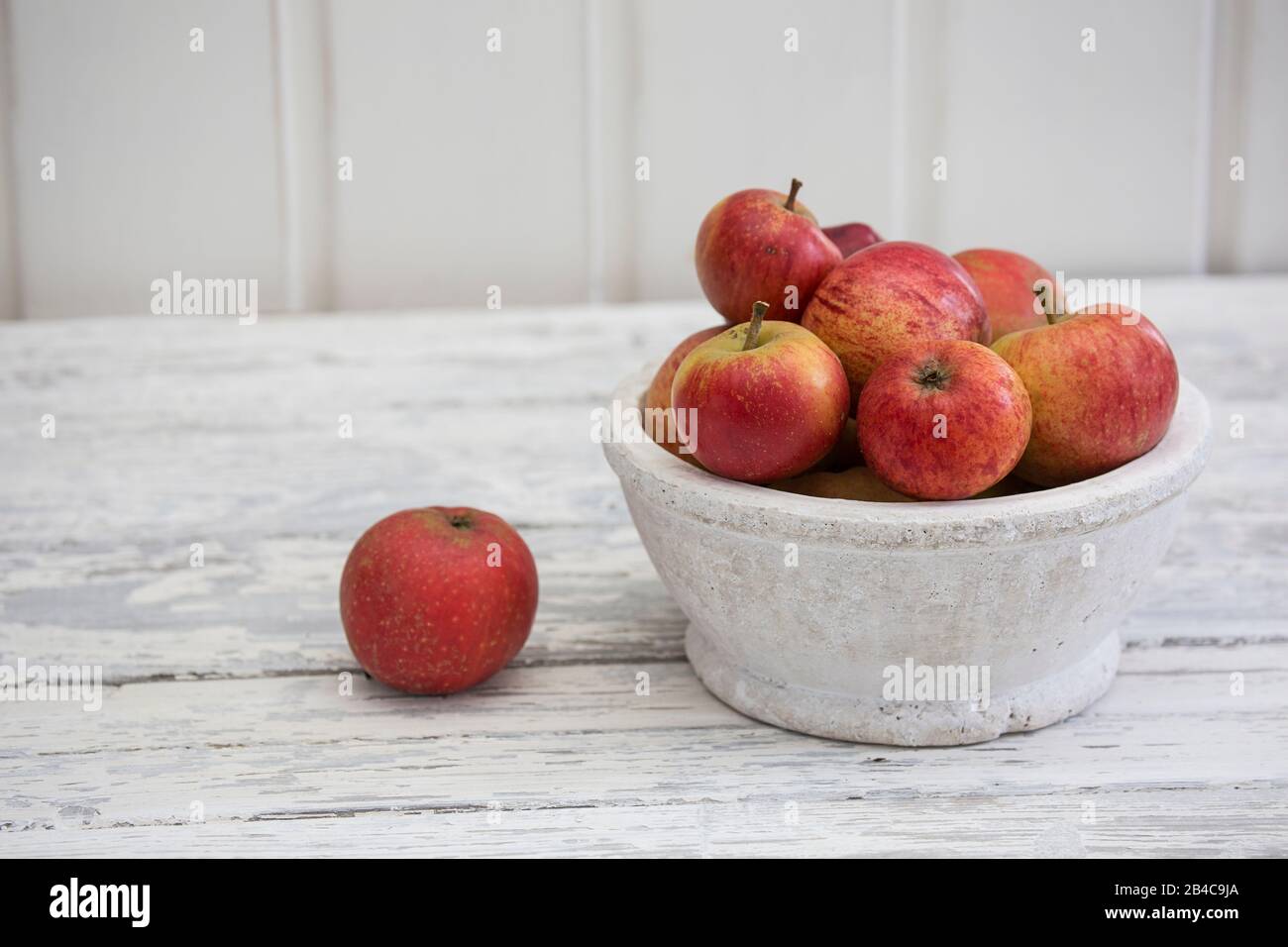 ancora vita con mele rosse in stile scandinavo su legno bianco Foto Stock