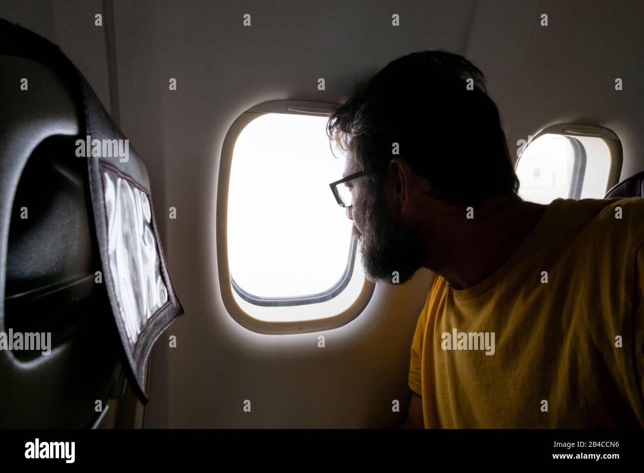 Viaggiatore barbuto uomo guarda fuori dalla finestra all'interno della aiplane volare e viaggiare - Turismo e vacanze rtip concetto con persone adulte e voli Foto Stock
