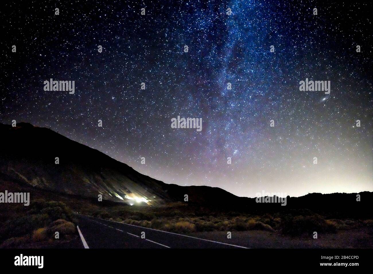 Concetto di viaggiare in incredibili luoghi panoramici con una lunga strada asfaltata di notte e la via lattea stelle sul cielo nero Foto Stock