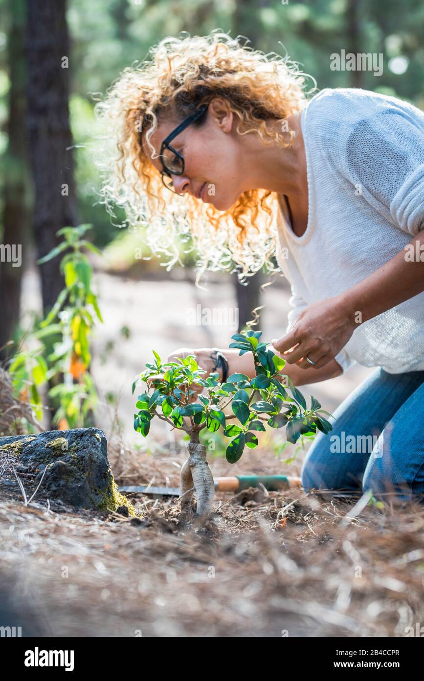 Ambiente concetto con bella curly giovane donna adulta prendersi cura di nuove piante nella foresta - salvare il pianeta e bella gente fermare la deforestazione e salvare le foreste per il futuro verde Foto Stock