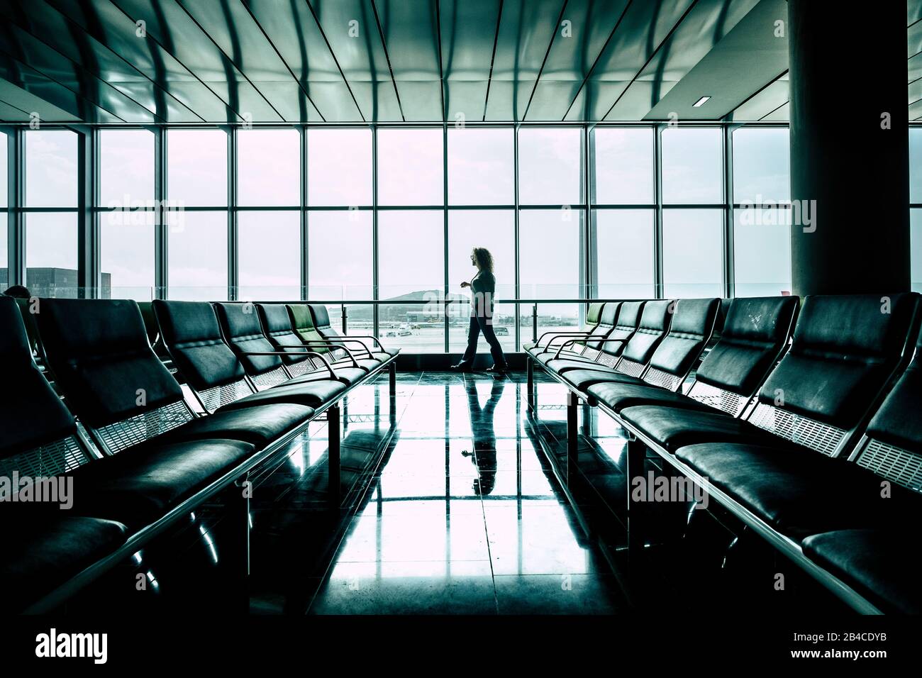 Donna che cammina al gate dell'aeroporto in attesa del volo iniziare per attività di affari o di vacanza - volo ritardato o annullato - diritti e assicurazione per il concetto di viaggiatori Foto Stock