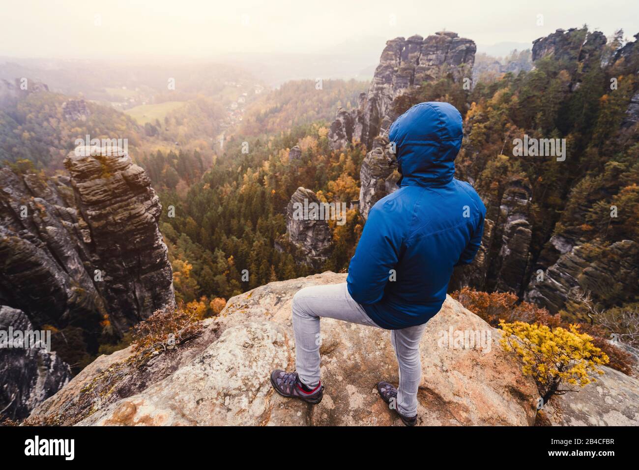 Wanderer steht auf dem Gipfel eines Berges, genießt die Aussicht über Berge und Wälder im tal, Reise-Lifestyle-Abenteuer-Konzept Foto Stock
