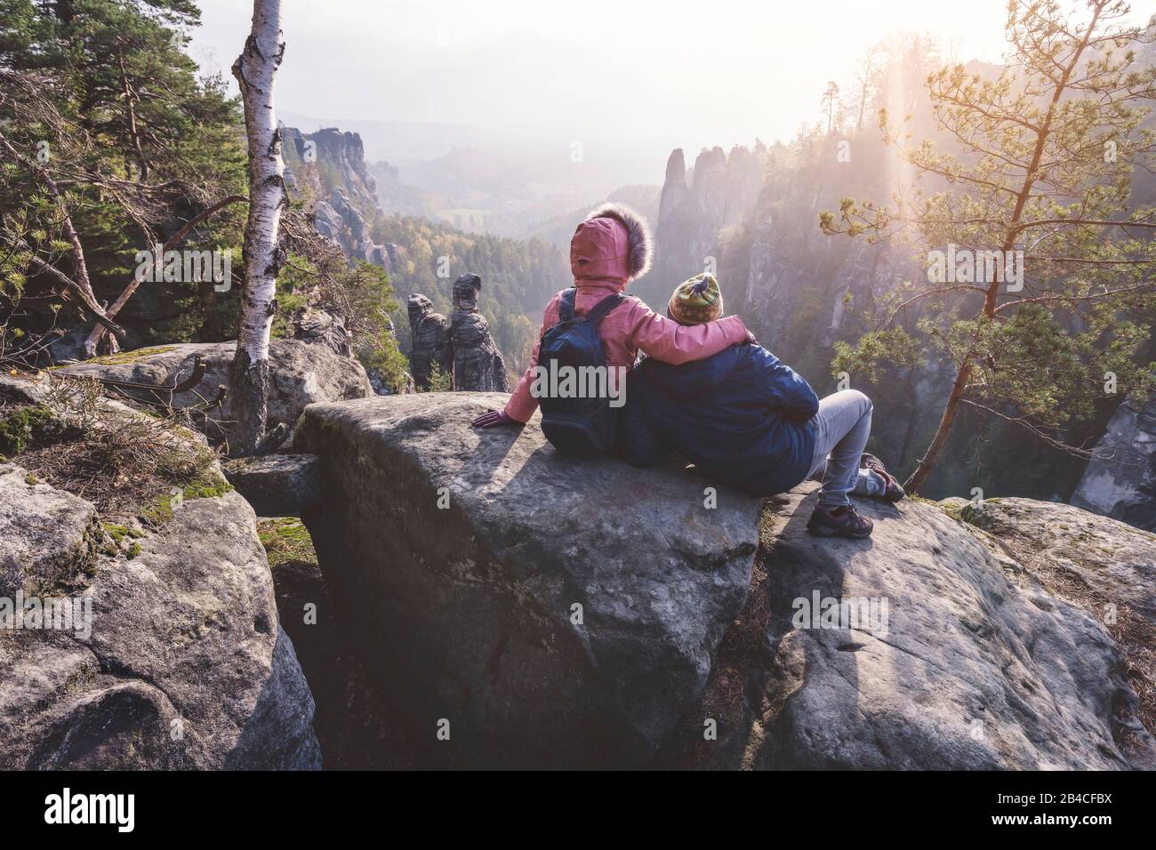Junges Paar in winterlicher Kleidung mit Rucksäcken, die nach Wanderung auf einem Kalksteinfelsen sitzend die Ansicht der Landschaft genießt, Reise-li Foto Stock