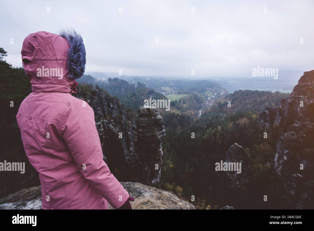 Junge Frau in winterlicher Kleidung im Freien, die allein auf einem Berg steht und die Aussicht genießt, Reiselebensstil-Harmoniekonzept, Rückansicht Foto Stock