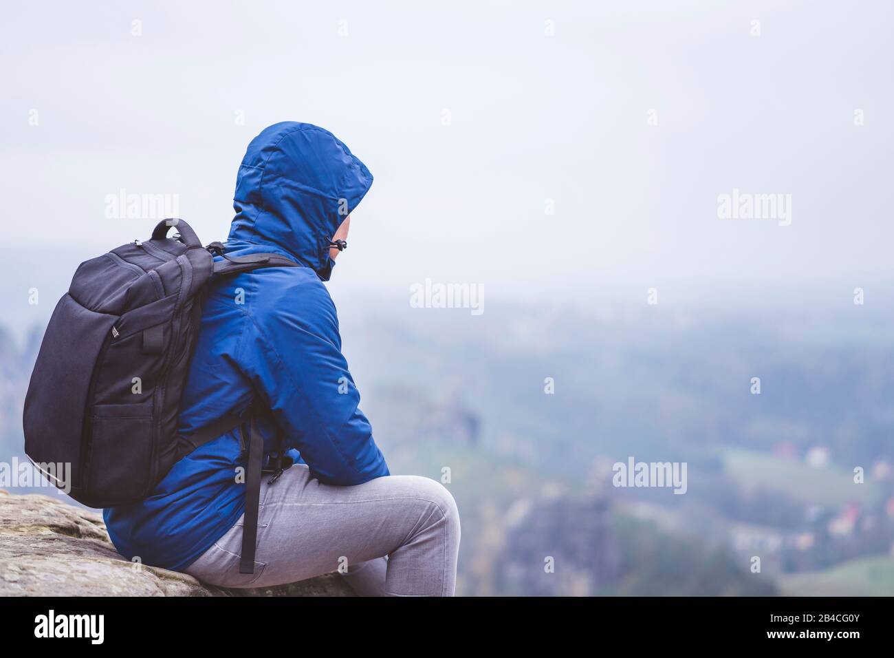 Wanderer mit Rucksack sitzt auf einem Felsen und genießt die Aussicht ins tal, Reiseabenteuerlebensstil-Harmoniekonzept Foto Stock