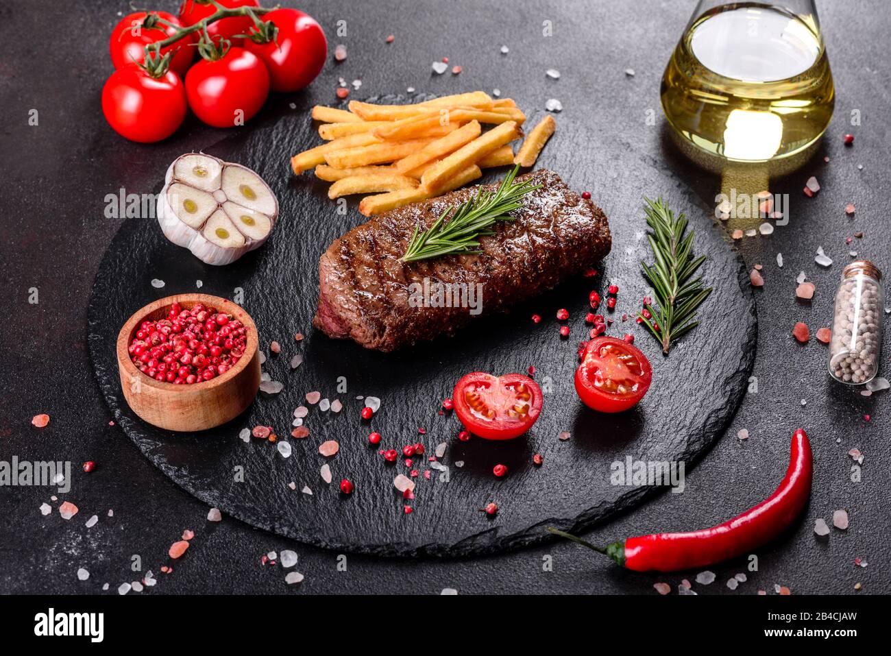 Bistecca Ribeye con patate, cipolle e pomodori ciliegini. Bistecca succosa con burro aromatizzato Foto Stock