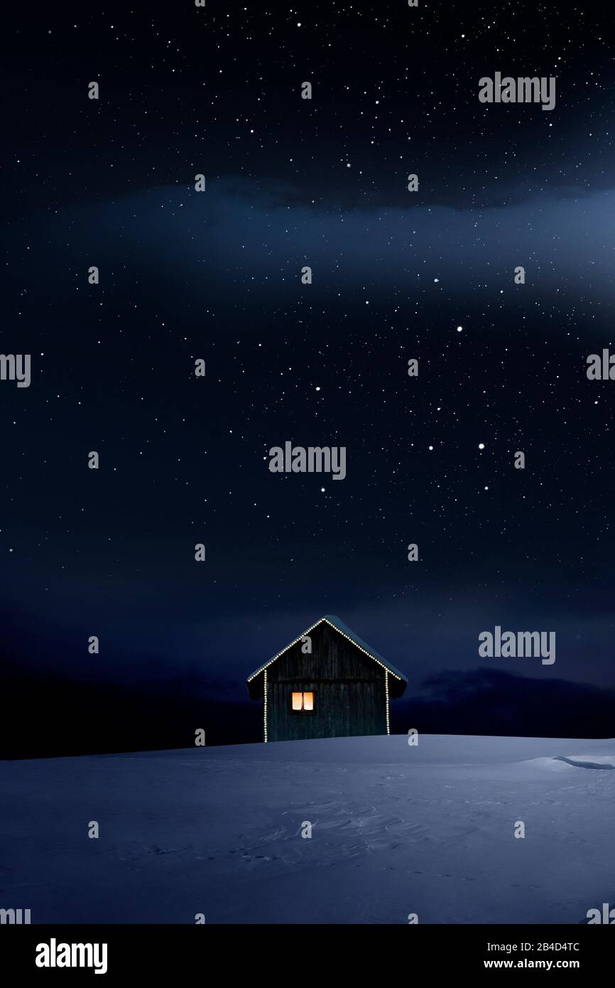 Rifugio illuminato da Natale in fredda notte invernale con cielo stellato Foto Stock