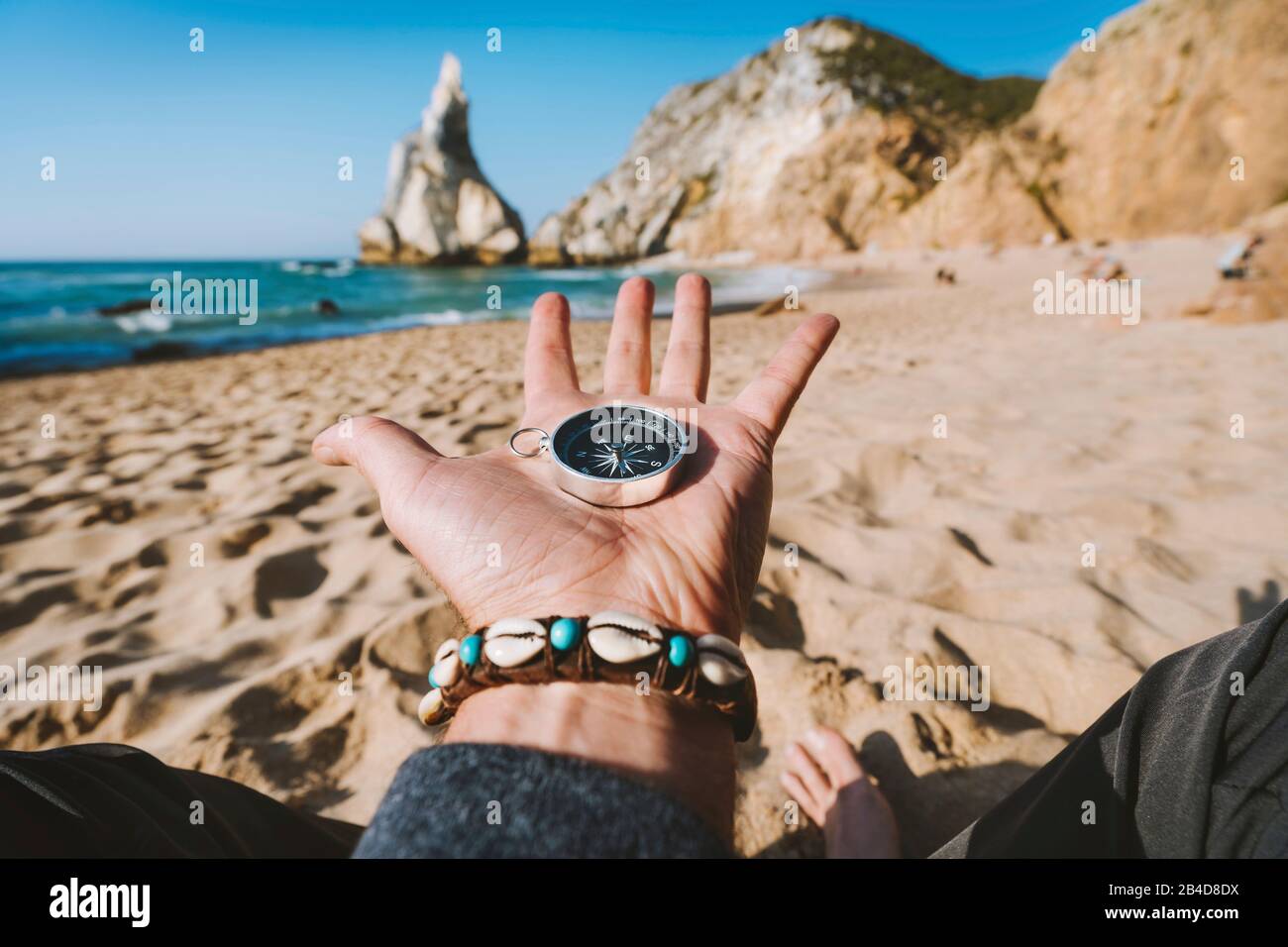Bussola a mano aperta che simboleggia il concetto di ricerca avventura contro la spiaggia di Ursa, Sintra, Portogallo. Foto Stock