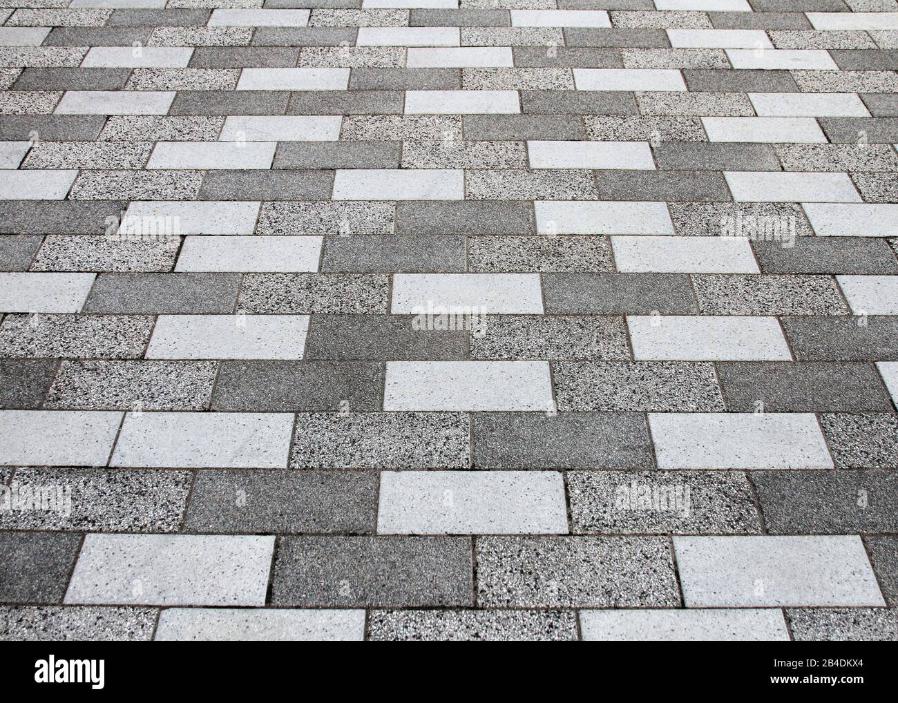Una vista in prospettiva di piastrelle di marciapiede grigio e bianco che formano un modello astratto. Foto Stock
