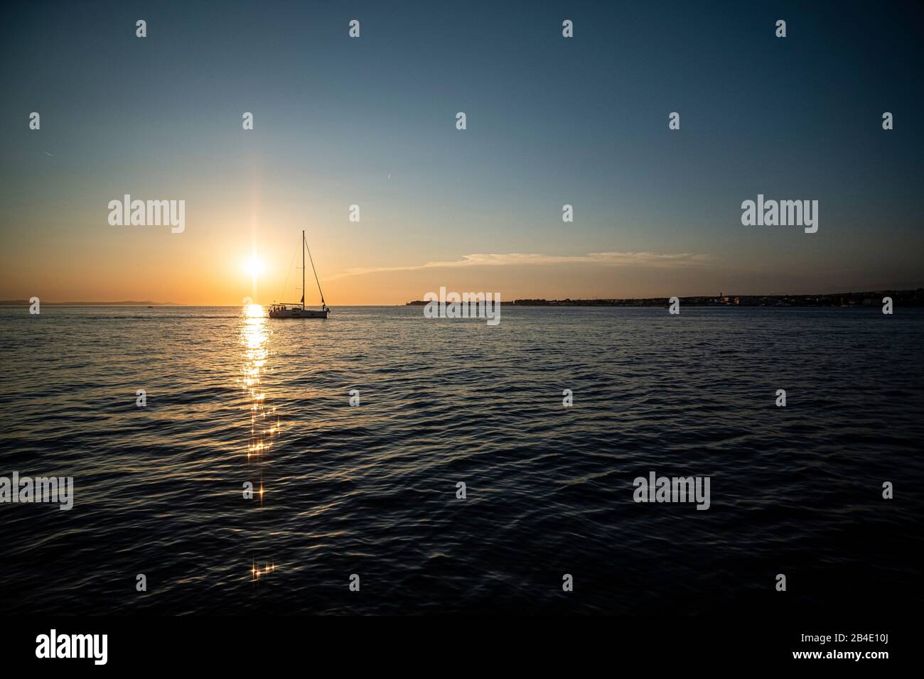 una barca a vela nel suggestivo tramonto sul mare Foto Stock