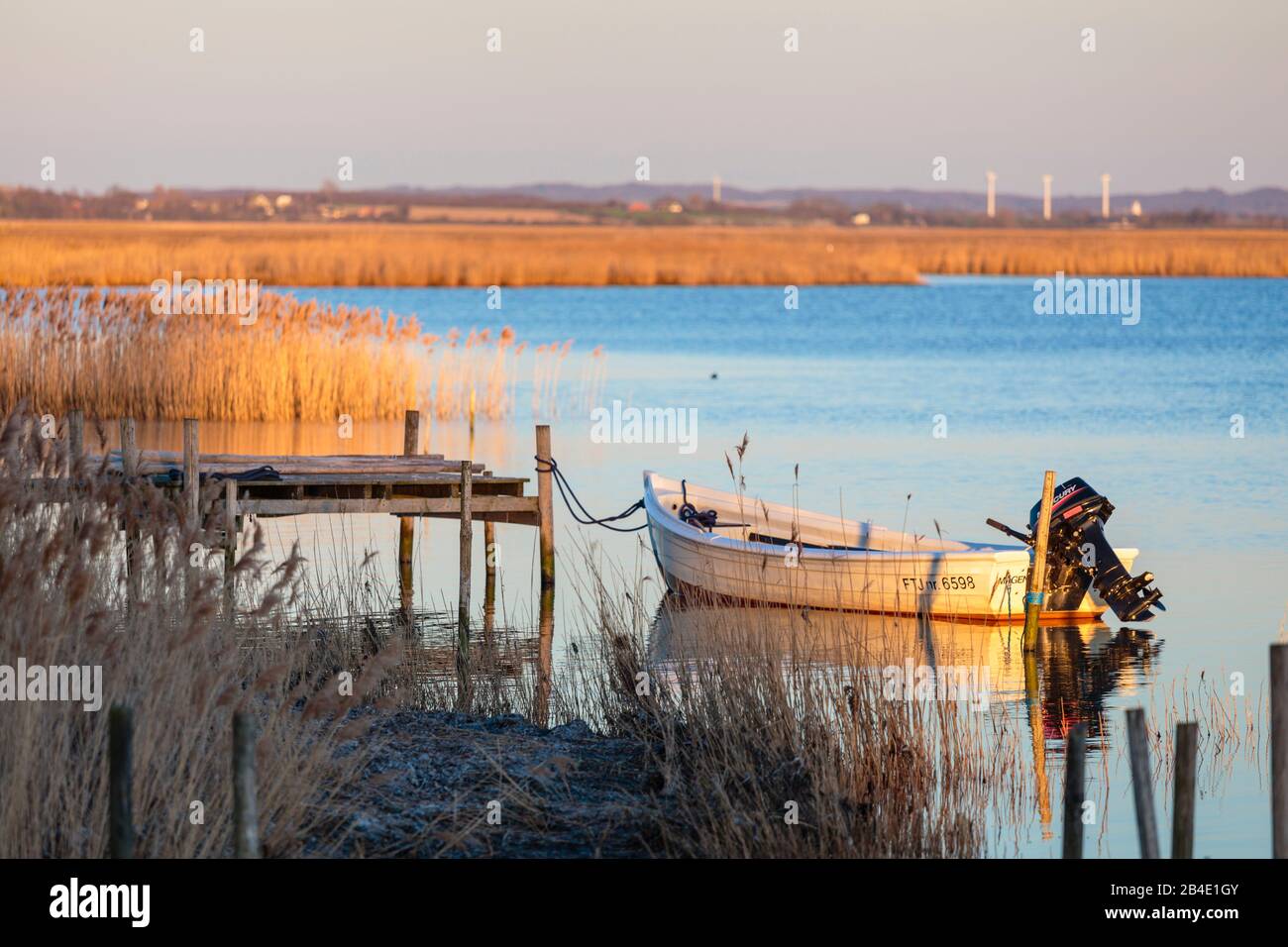 Europa, Dänemark, Møn, Kleines Motorboot an einem Steg vor Nyord, dahinter die Salzwiesen des Naturreservats, Foto Stock