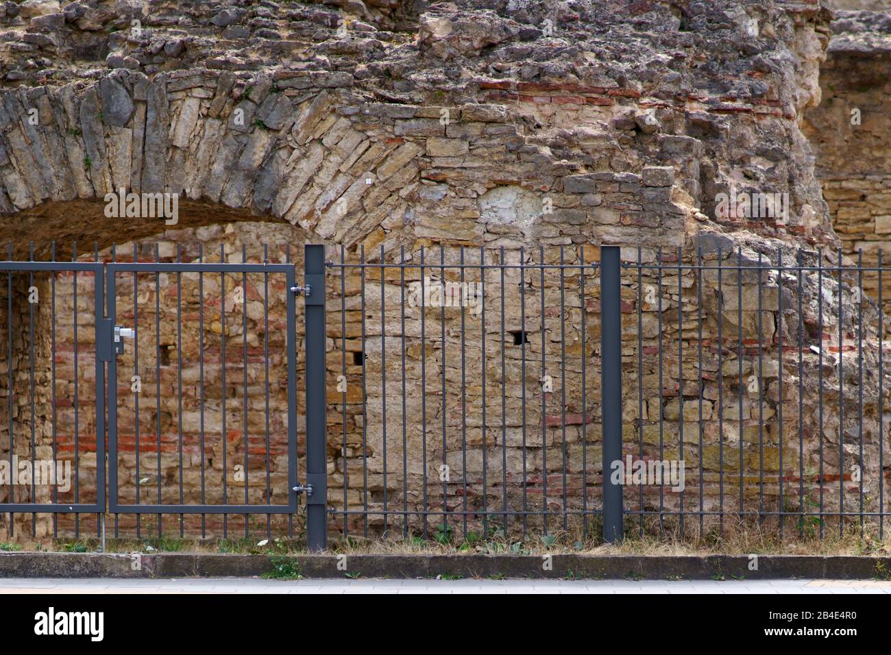 Un recinto con una porta di fronte alle antiche mura di un anfiteatro romano. Foto Stock