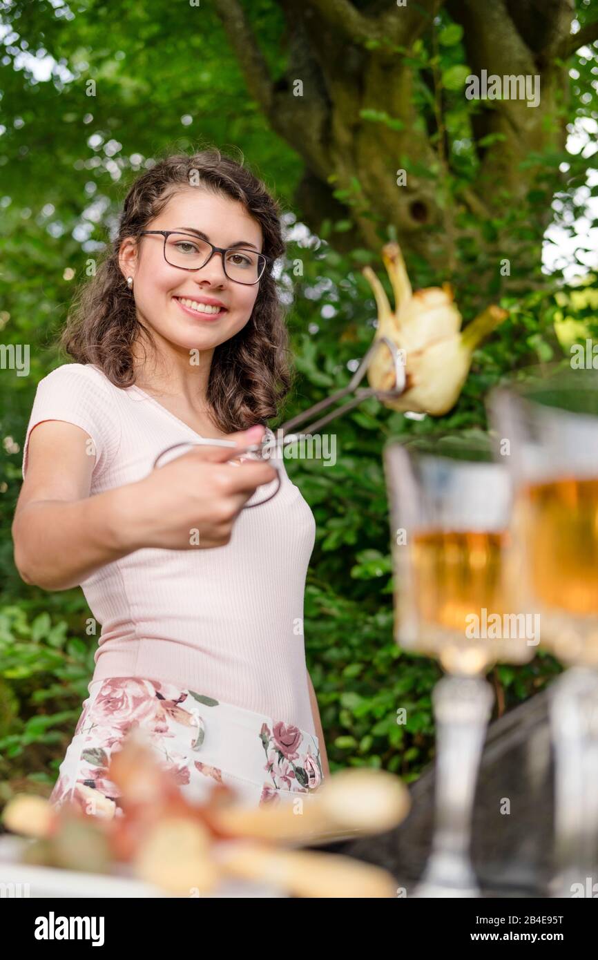 Junge Frau grillet im Garten, Grillfest Foto Stock