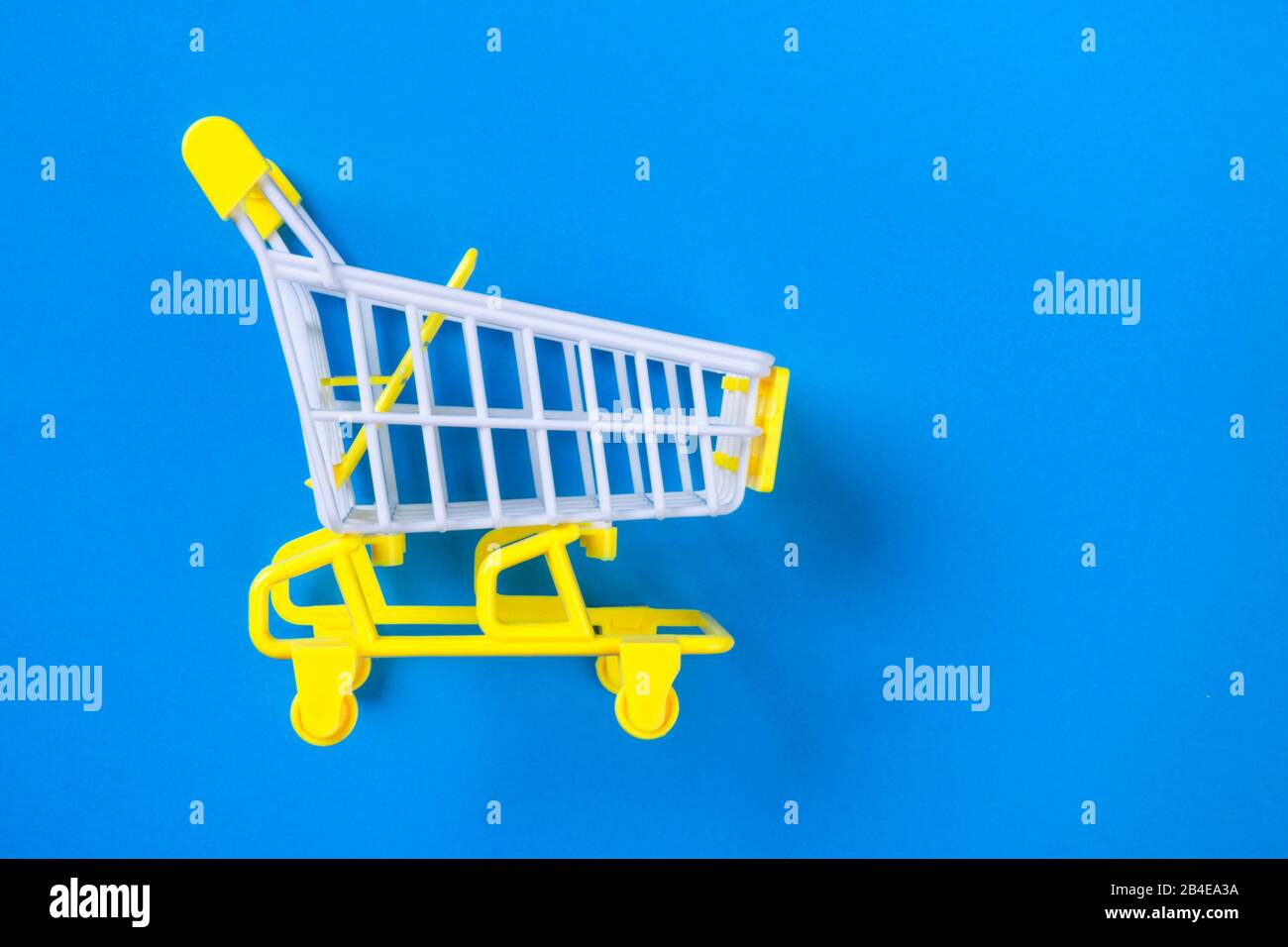 Shopping piccolo trolley su sfondo blu, Copy space. Vendita o acquisto di concetto di consumatore Foto Stock
