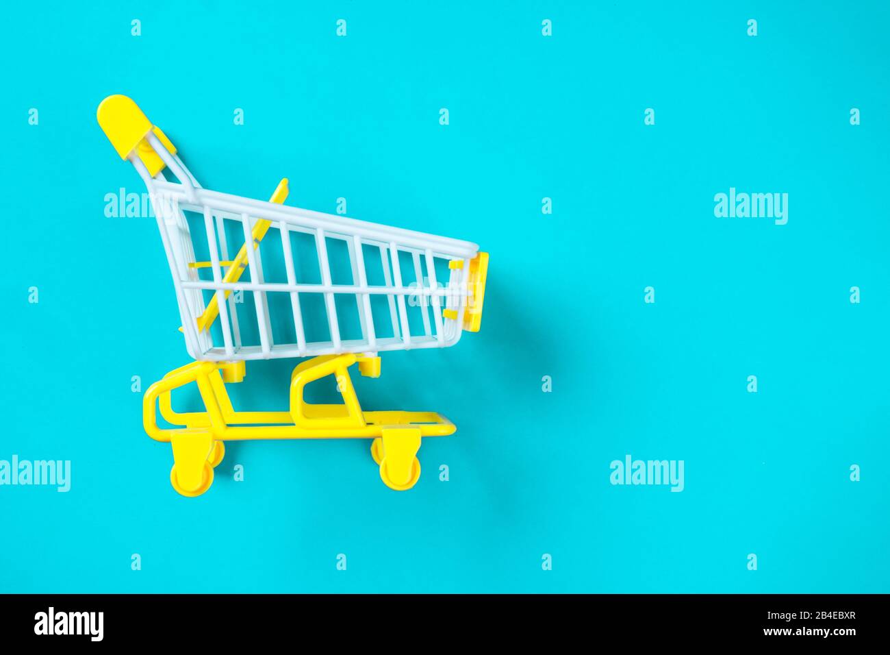 Shopping piccolo trolley su sfondo blu, Copy space. Vendita o acquisto di concetto di consumatore Foto Stock