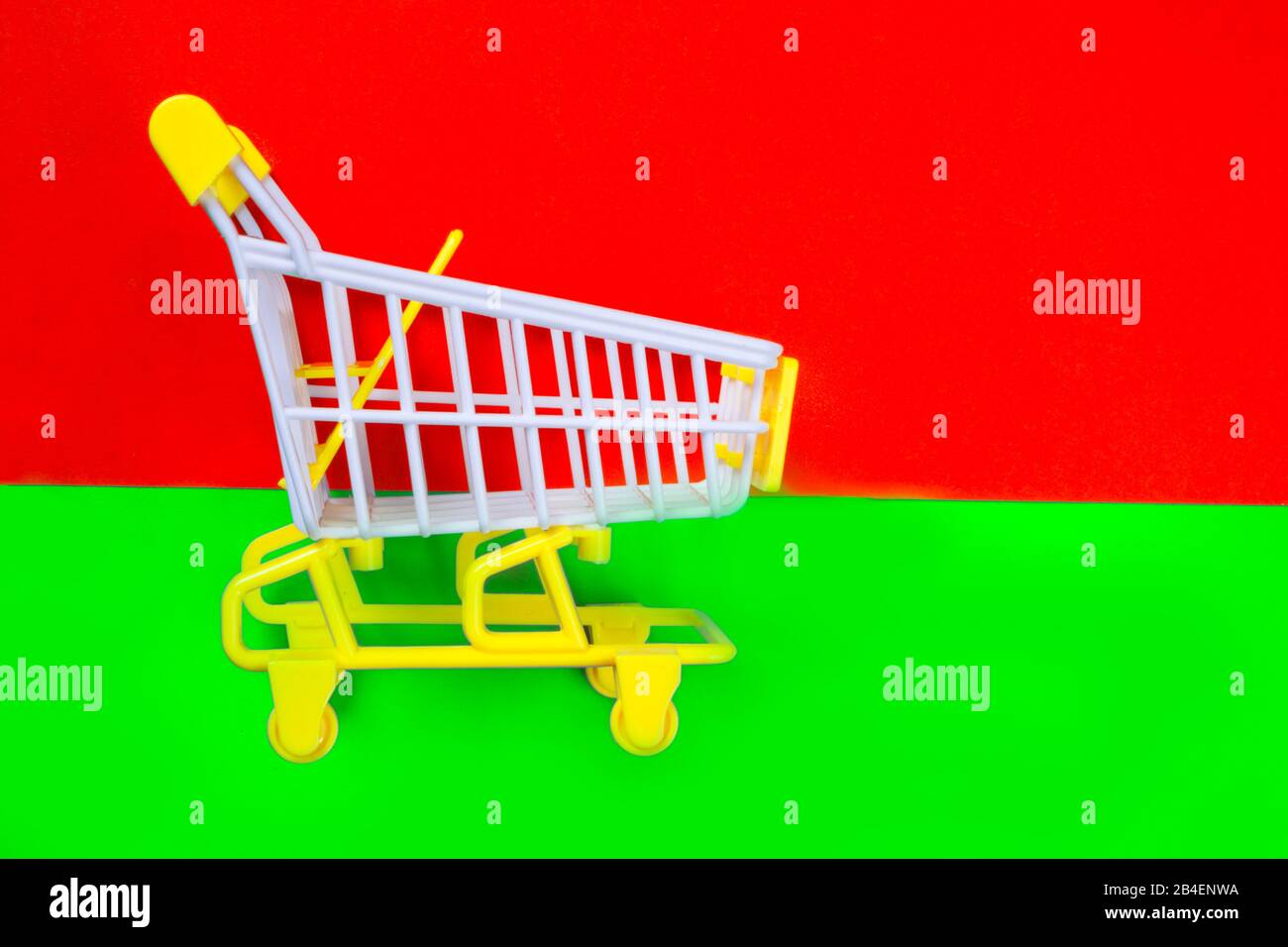 Shopping piccolo trolley su sfondo verde e rosso, Copy space. Vendita o acquisto di concetto di consumatore Foto Stock