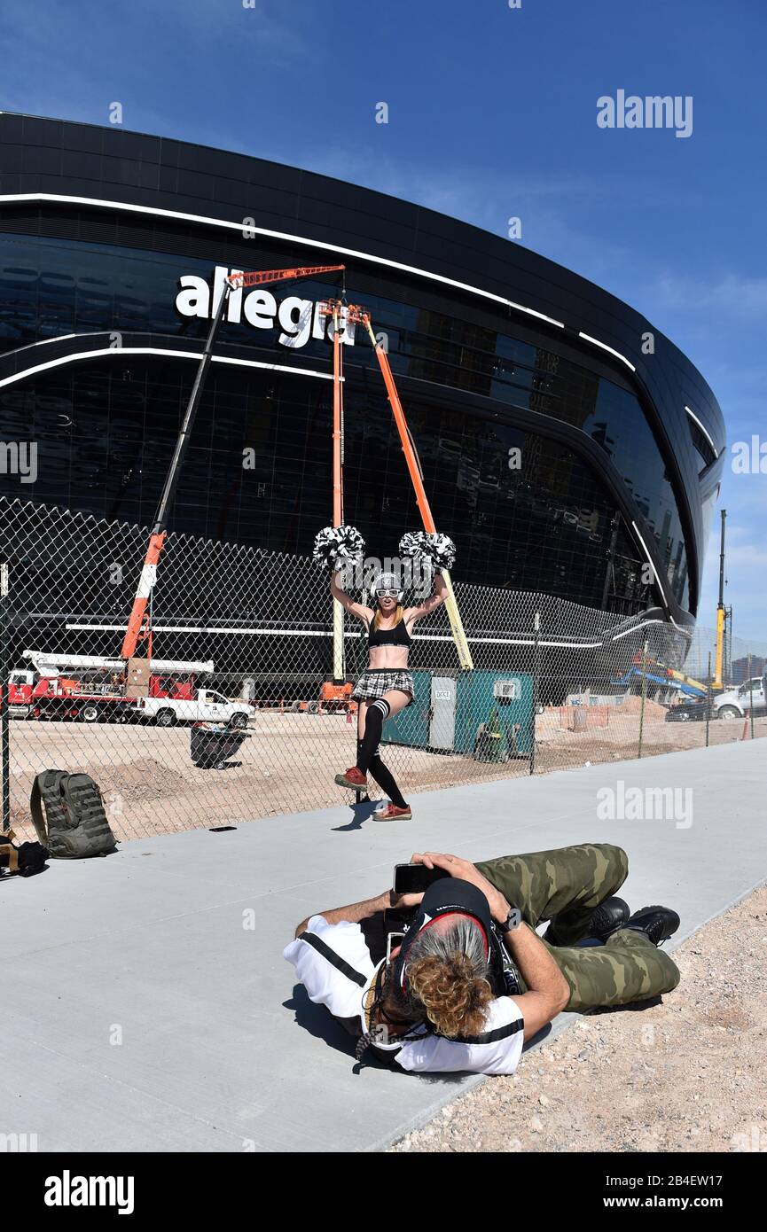 Las Vegas, Nevada, Stati Uniti. 6th Mar, 2020. Joy Lightowler, vestito da cheerleader, di Las Vegas si esibisce per un video mentre i lavoratori installano la segnaletica sullo stadio Allegiant, sede dei Las Vegas Raiders e del football UNLV. Lo stadio a cupola da 1,8 miliardi di dollari, 65.000 posti, dovrebbe essere aperto nell'agosto 2020 con l'inizio della stagione NFL. Credit: David Becker/Zuma Wire/Alamy Live News Foto Stock