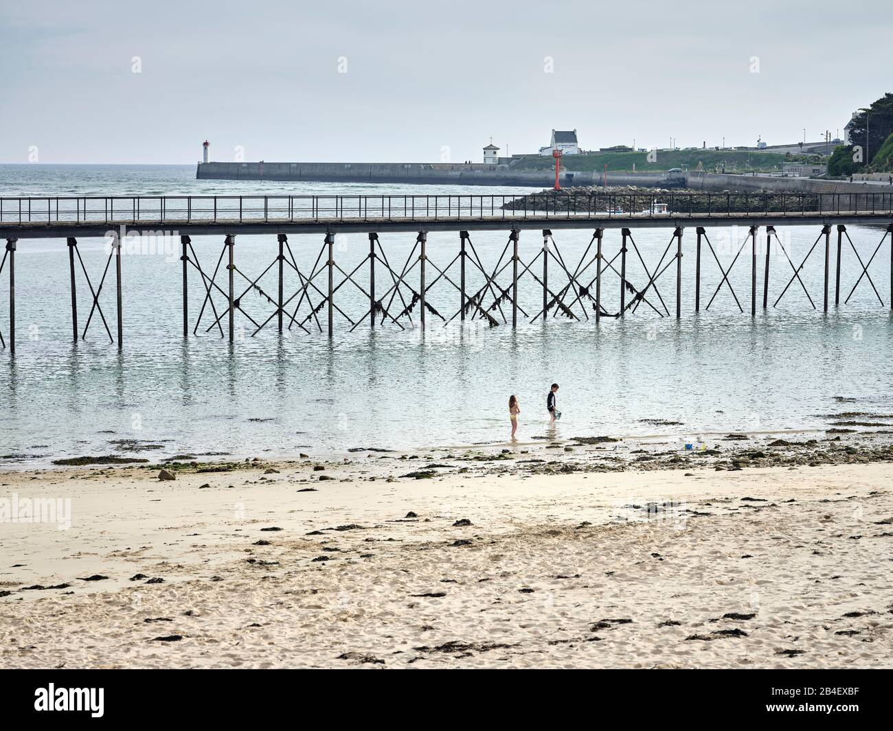 Spielende Kinder am Strand von Capusins mit dem Steg im Hintergrund a Audierne in der Bretagne. Foto Stock
