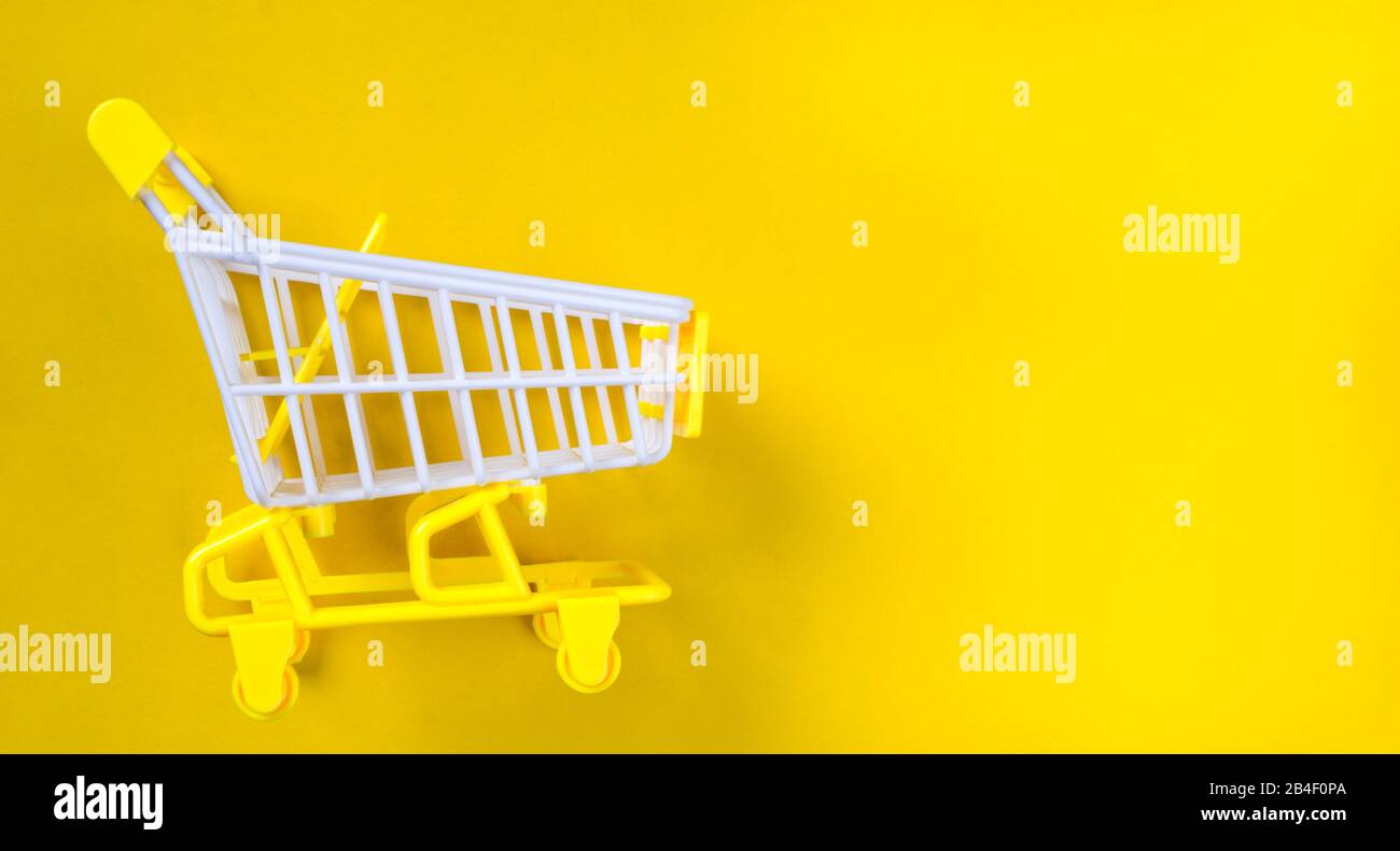 Shopping piccolo trolley su sfondo giallo, Copia spazio. Vendita o acquisto di concetto di consumatore Foto Stock