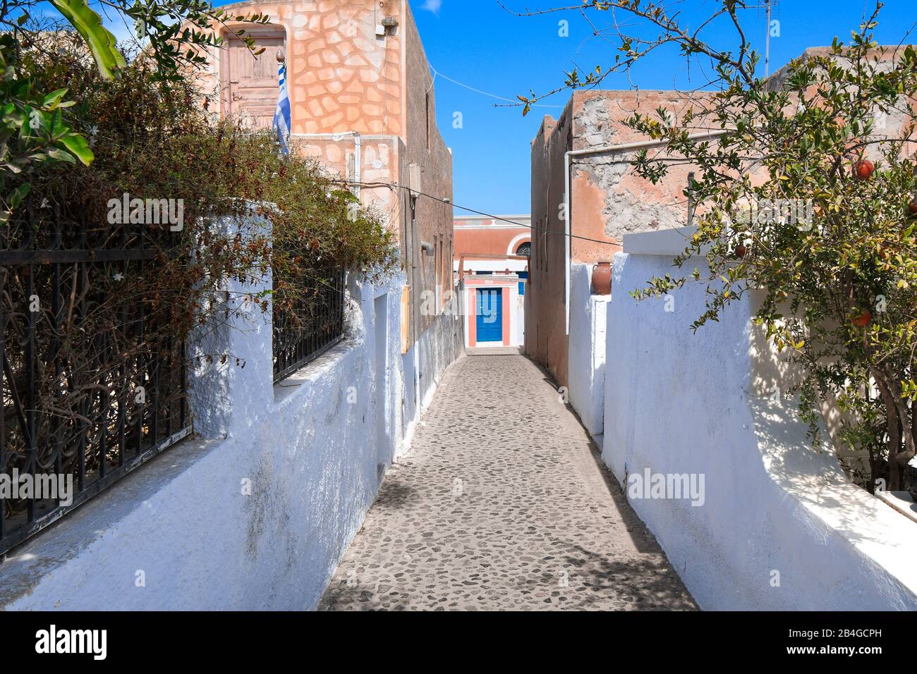 Uno stretto corridoio di pietra con una porta blu alla fine sull'isola di Santorini, Grecia. Foto Stock