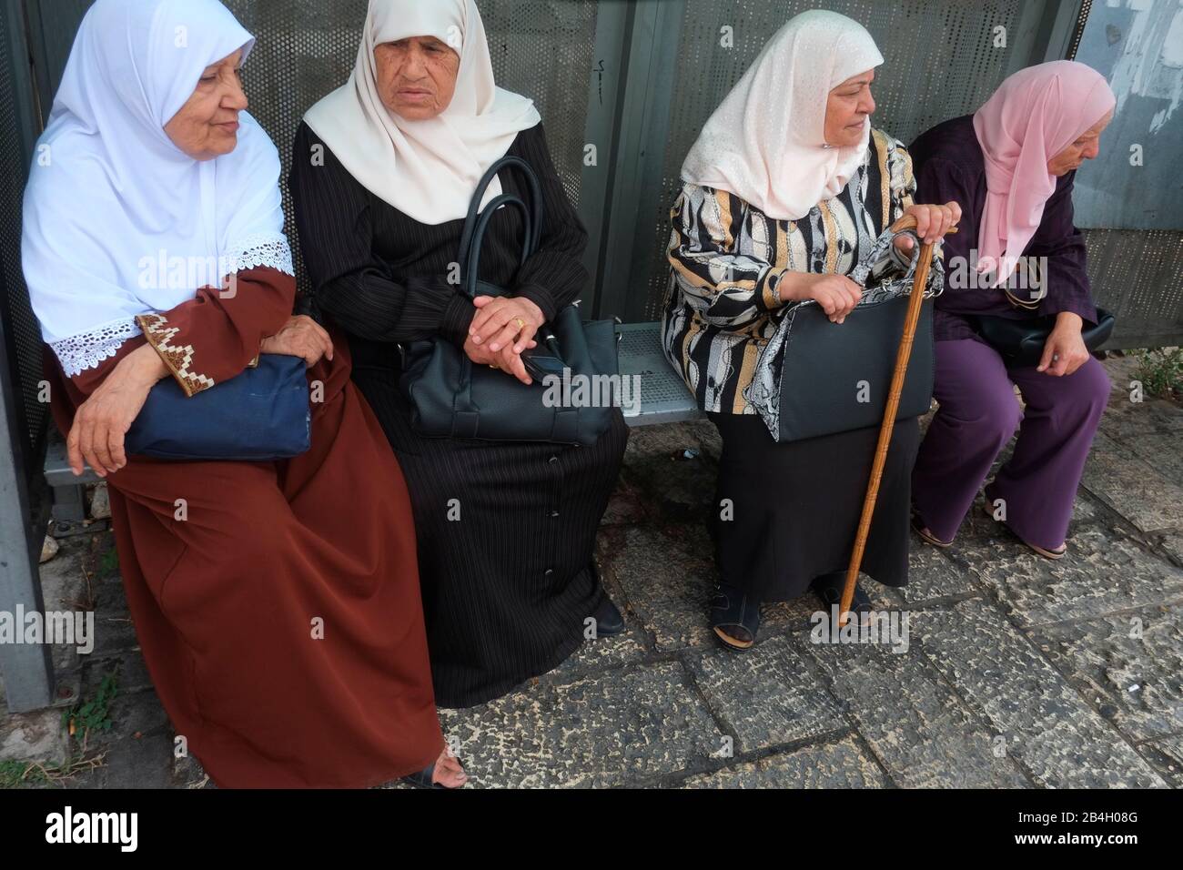 Donne musulmane che indossano hijab aspettano alla fermata dell'autobus. Un hijab è un velo indossato da alcune donne musulmane in presenza di qualsiasi maschio al di fuori della loro famiglia immediata, che di solito copre la testa e petto.attendere alla fermata dell'autobus Foto Stock