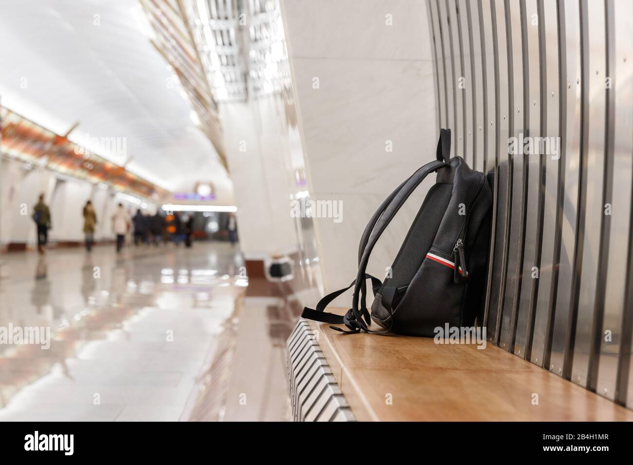 Zaino/borsa nera in pelle dimenticata o bomba per commettere un attacco terroristico si trova su un sedile nella stazione della metropolitana, i trasporti pubblici, passeggero sfocato su bac Foto Stock
